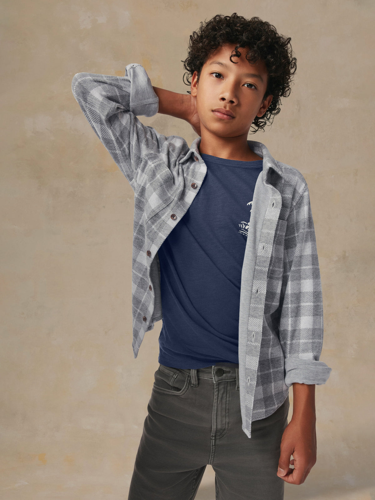 Close up of a child wearing a grey plaid button up shirt and grey pants, image 1 of 7