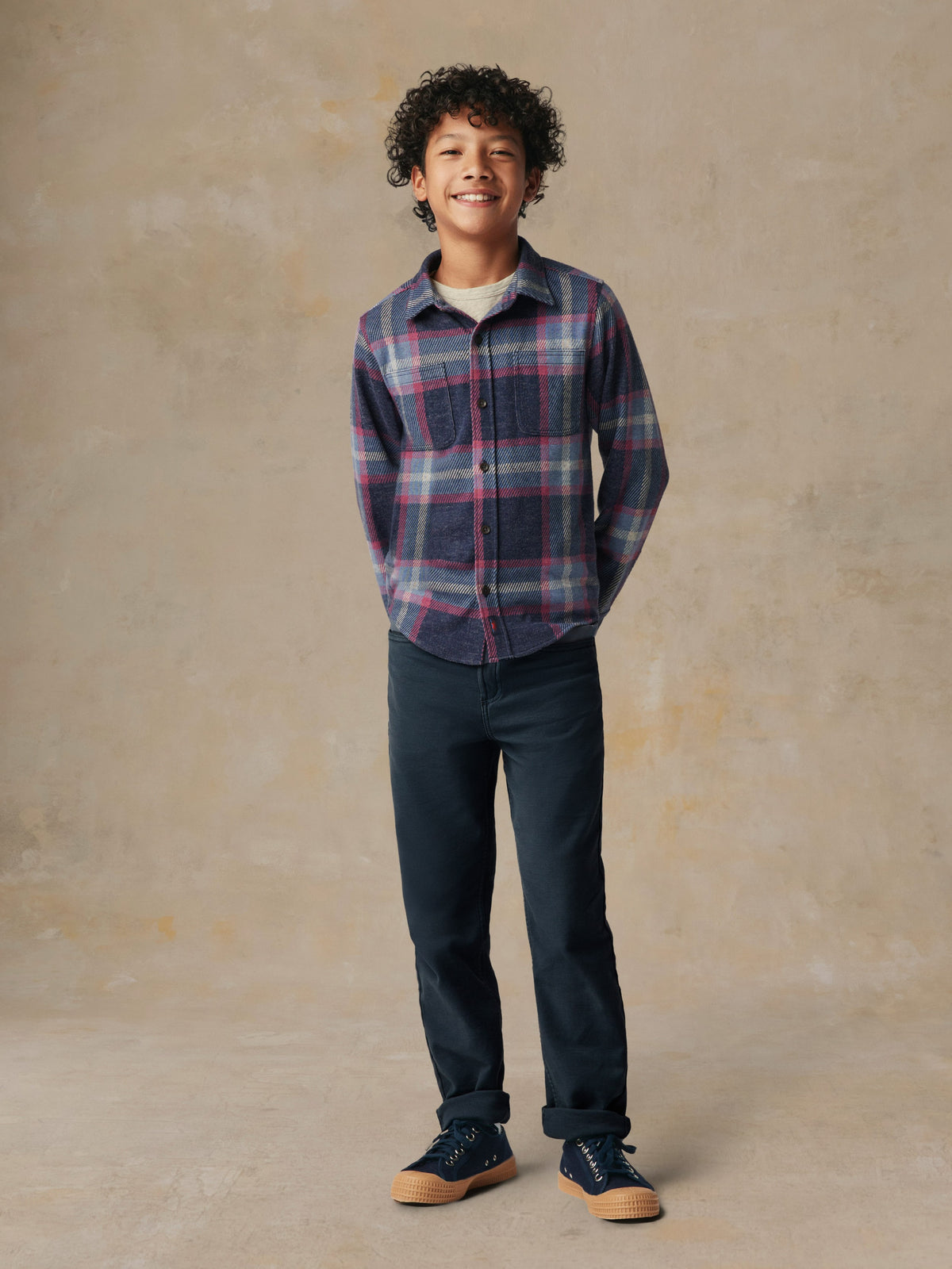 A child wearing a plaid button up shirt and black pants, image 1 of 6