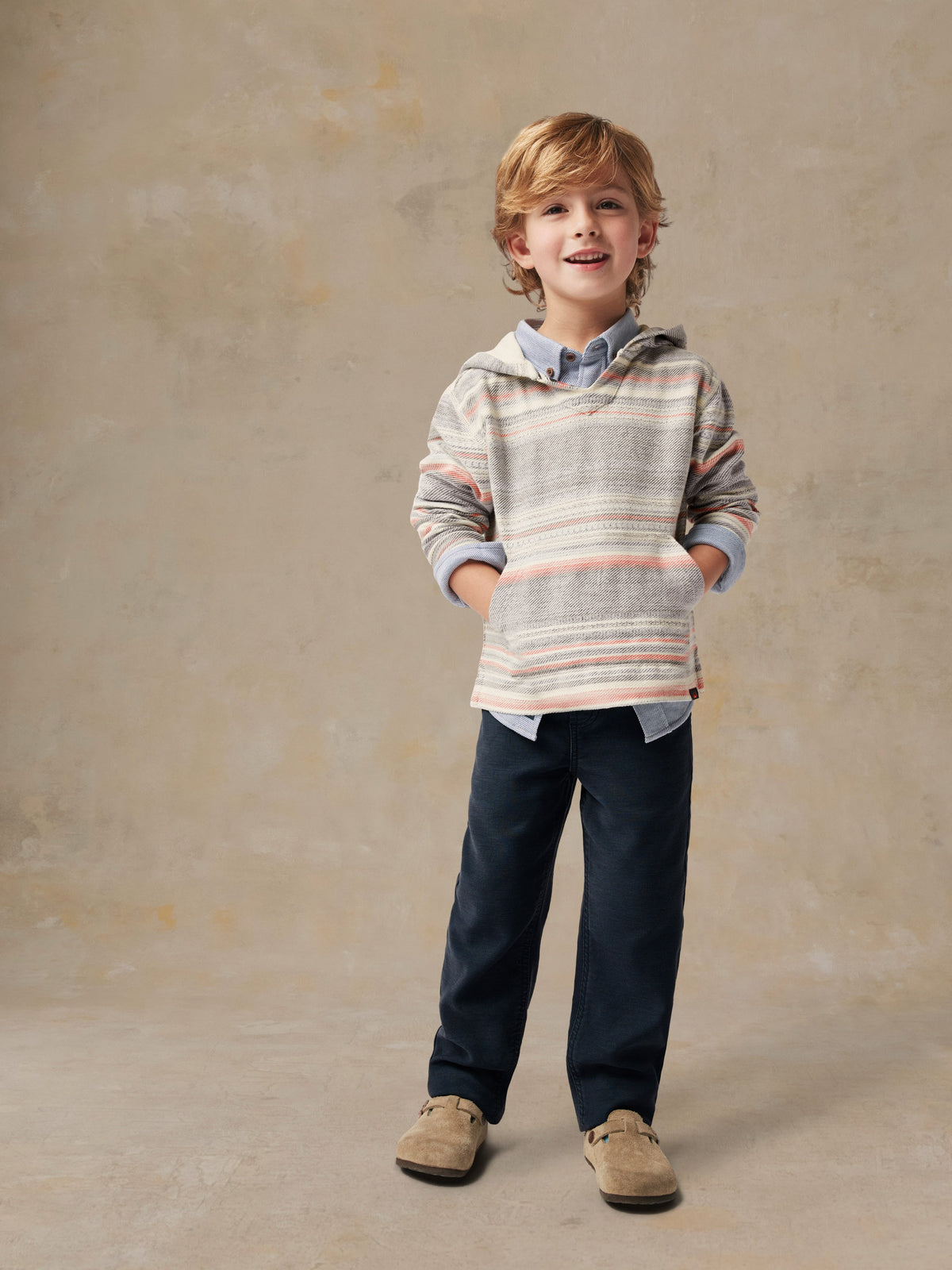 A boy wearing a striped hoodie and blue pants, image 3 of 4