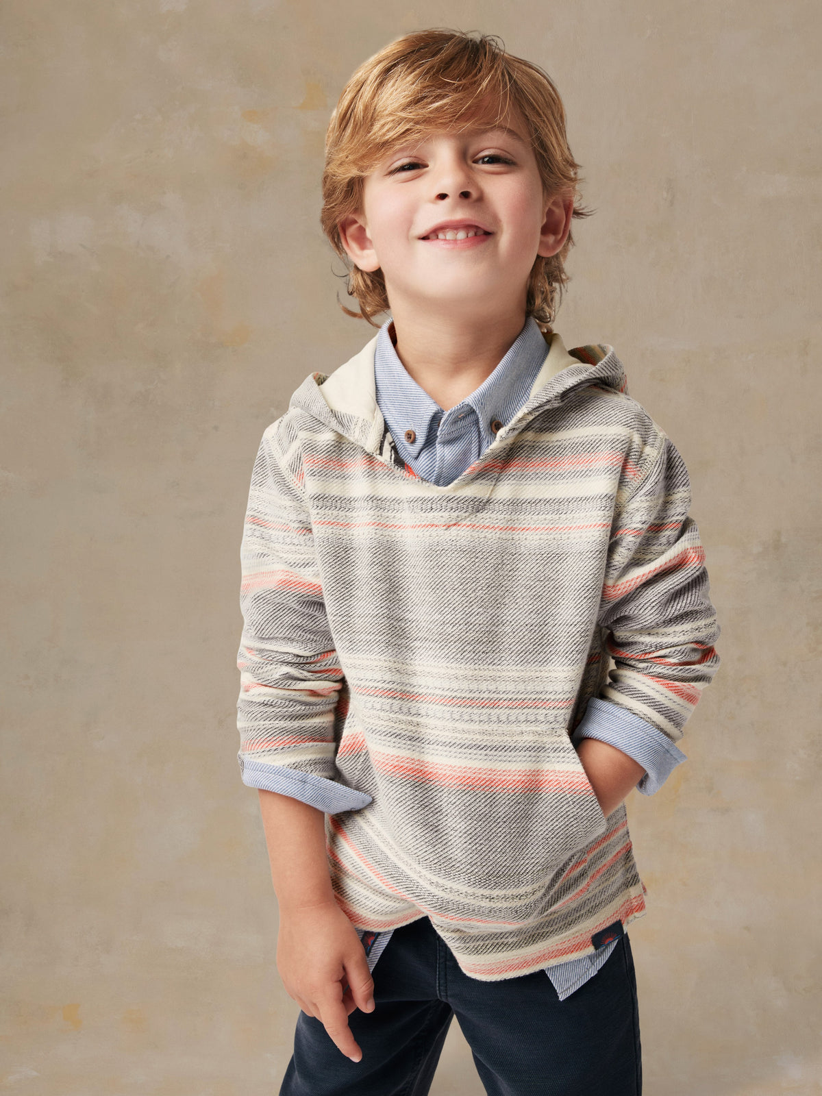A boy wearing a striped hoodie and blue pants, image 2 of 4