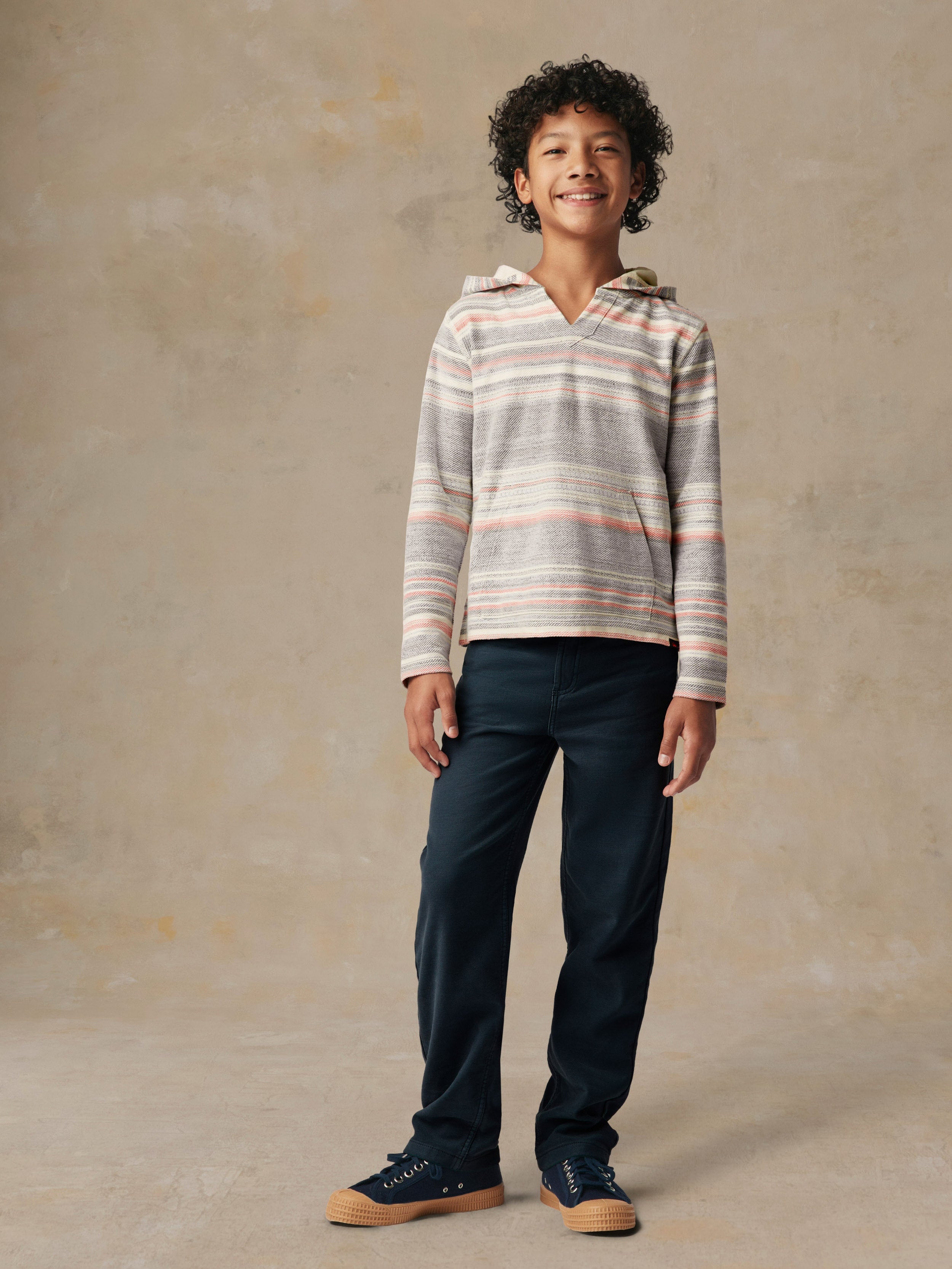 A kid wearing a striped hoodie and blue pants