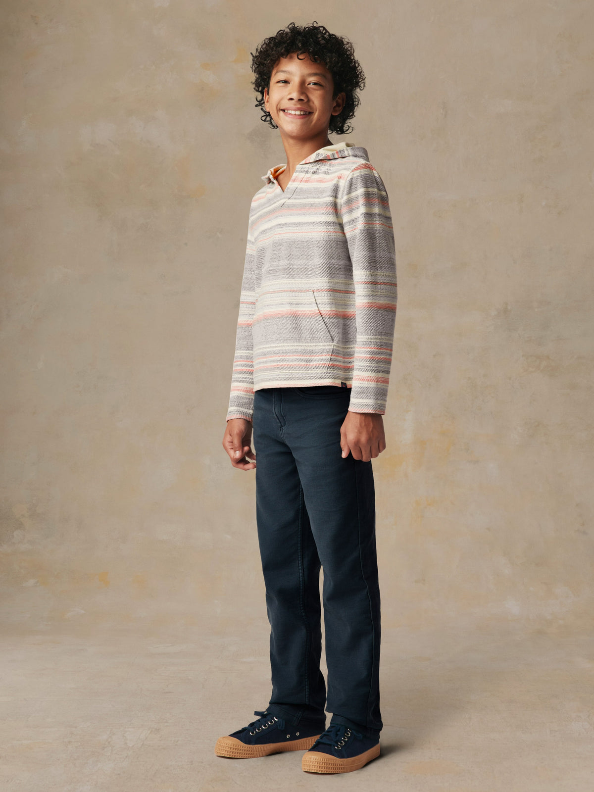 A kid wearing a striped hoodie and blue pants, image 4 of 5