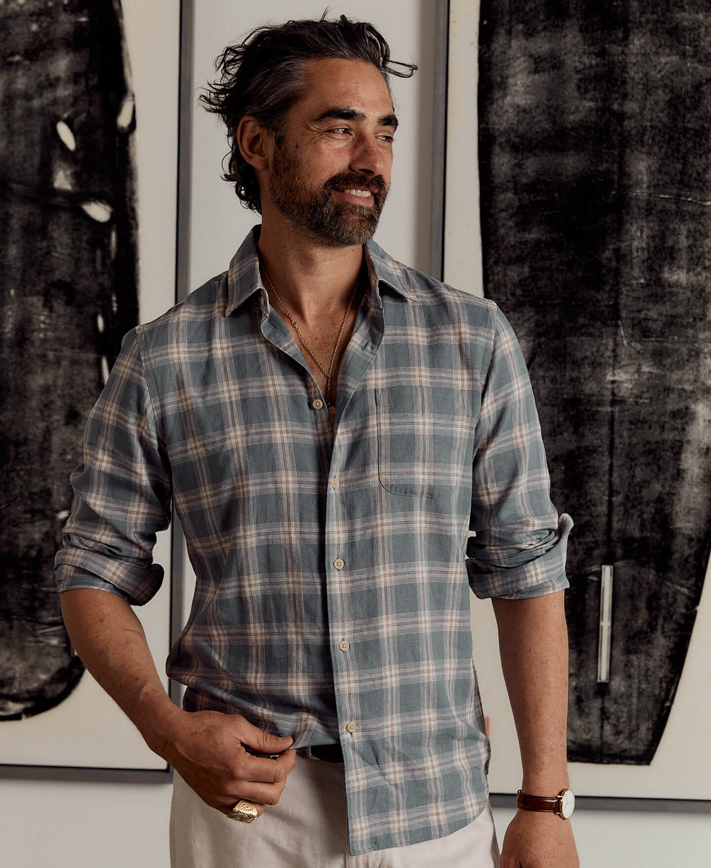 A male model wearing a palmetto plaid shirt with white movement linen pants 