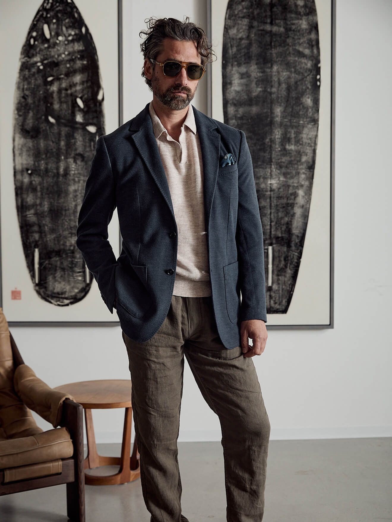 A male model wearing a knit polo with sunglasses, a linen blazer and dune utility pants.