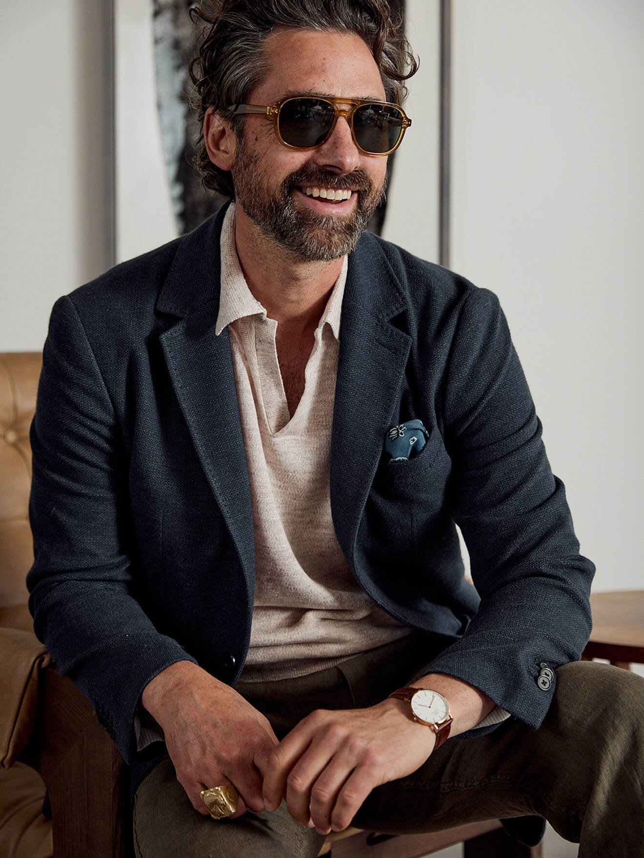 A male model wearing a knit polo with sunglasses, a linen blazer and dune utility pants.