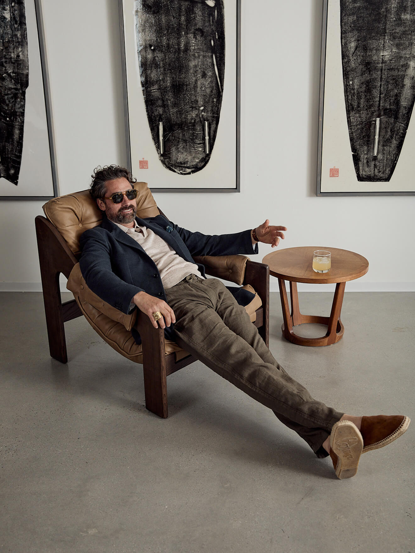 A male model wearing a knit polo with sunglasses, a linen blazer and dune utility pants.