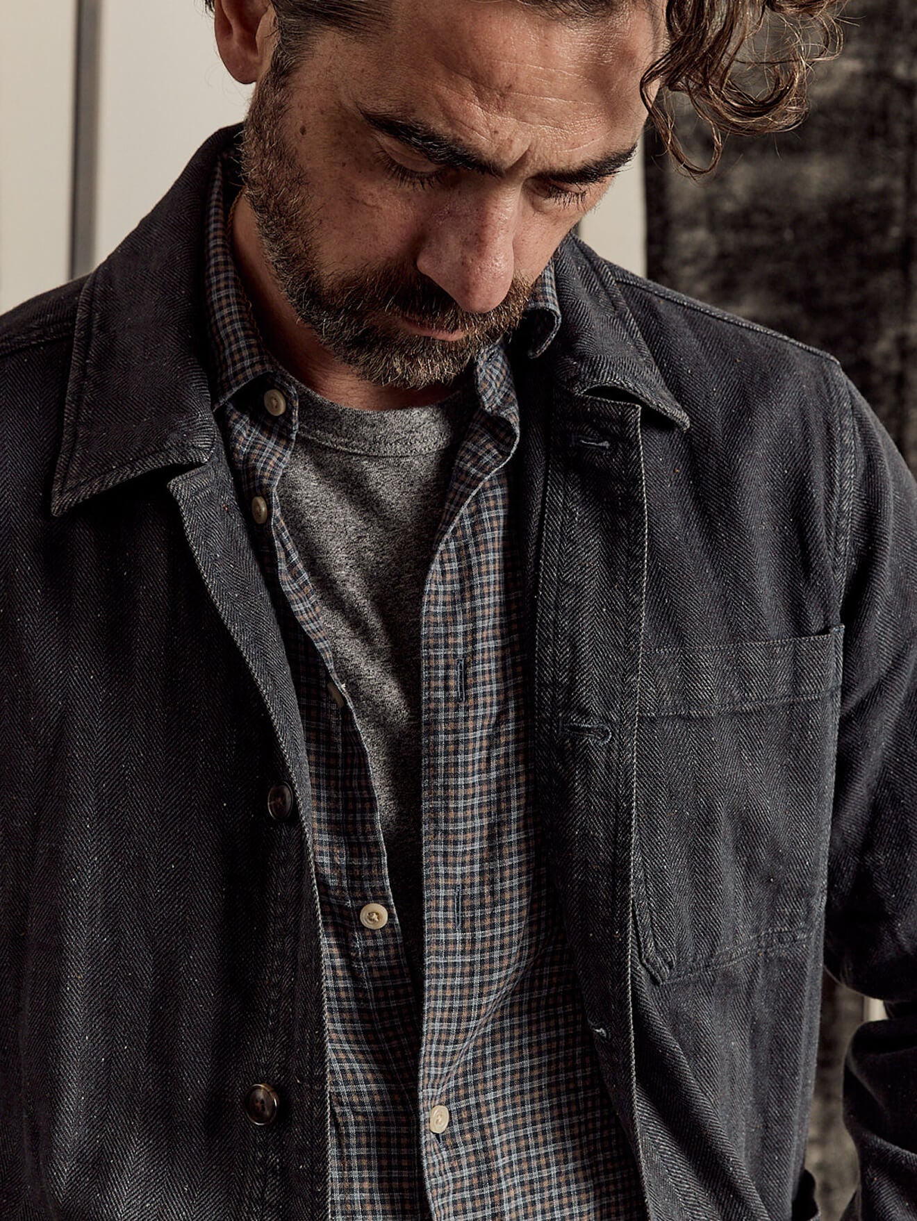 A male model wearing a sunwashed tee under the palmetto shirt, paired with an indigo herringbone studio jacket