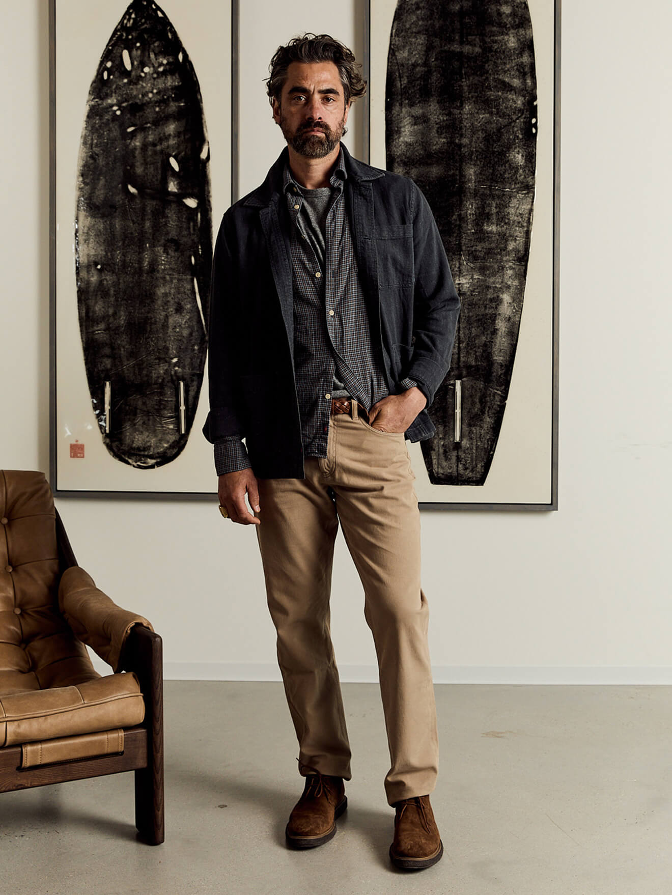 A male model wearing a sunwashed tee under the palmetto shirt, paired with an indigo herringbone studio jacket, reserve twill pants and reserve chukka boots