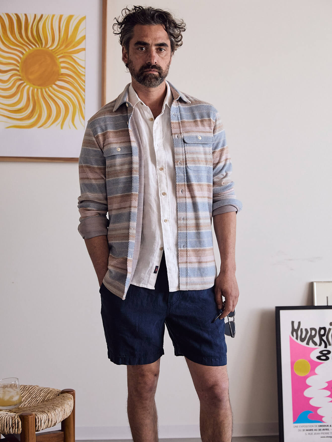 Male model wearing a legend shirt over a short sleeve white linen shirt and blue linen shorts