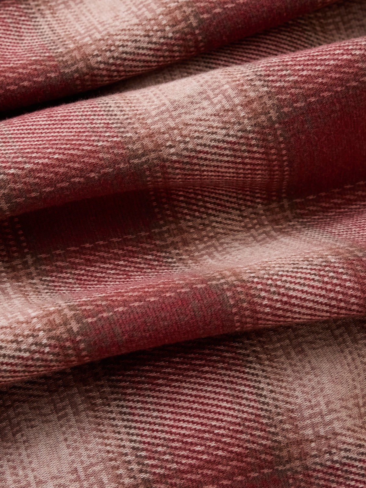 A close-up of draped plaid fabric in dusty rose, muted red, and beige tones, showing the woven texture and soft folds., image 2 of 3