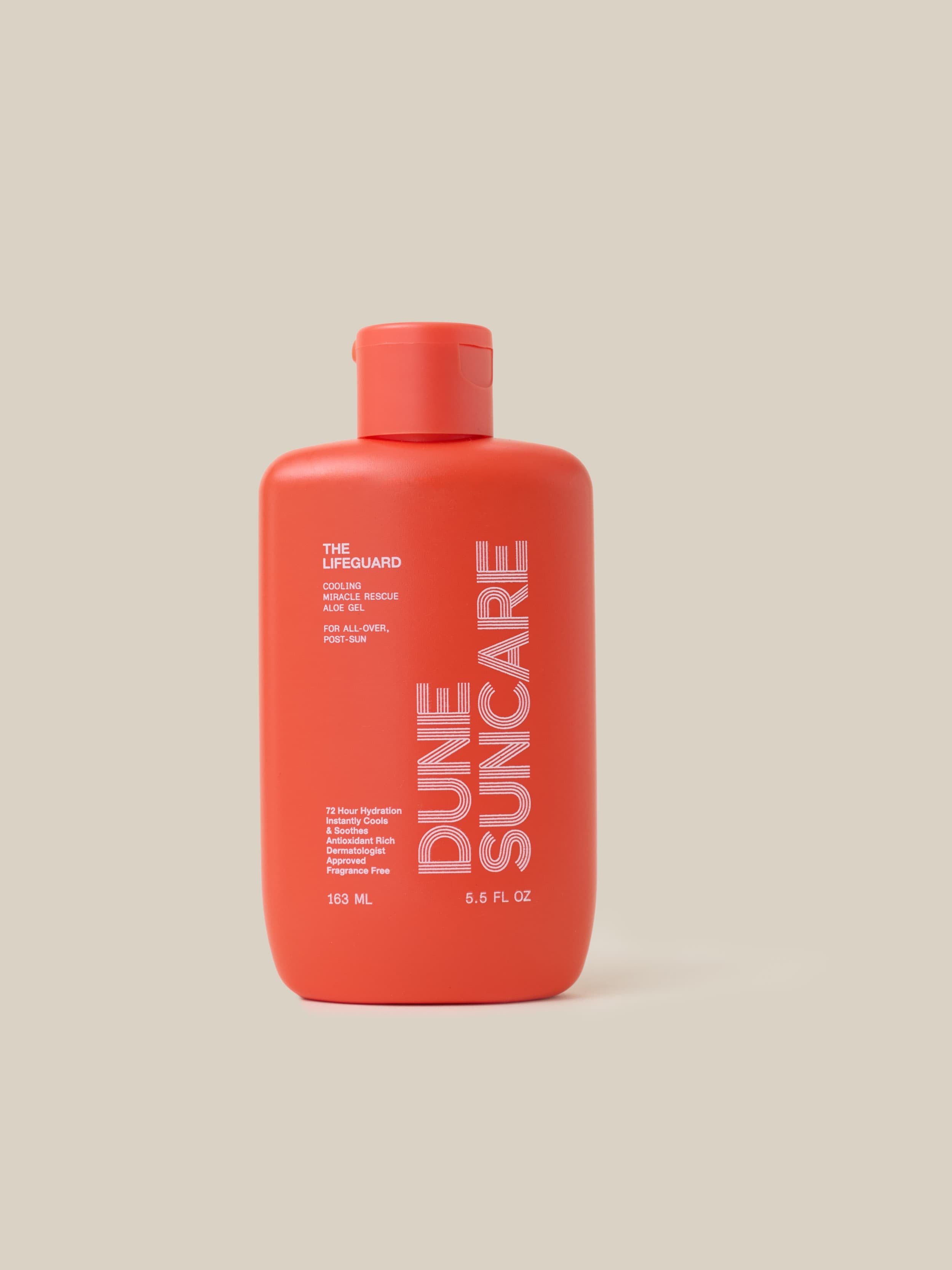 Red bottle of Dune Suncare on a beige background