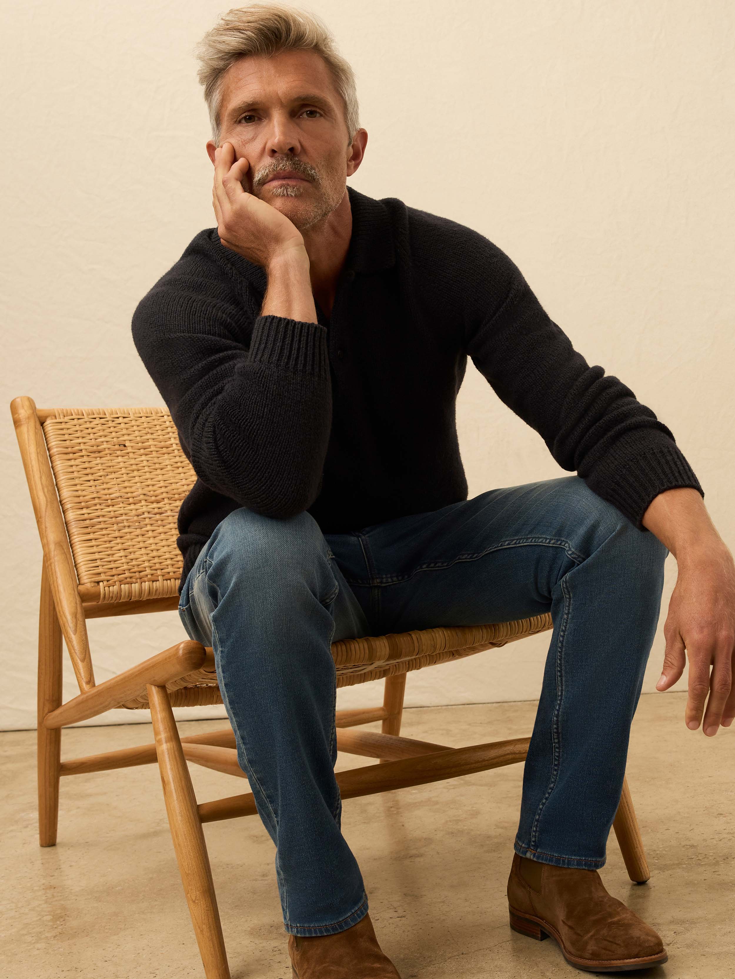 Man wearing a black long sleeve knit sweater against a beige background