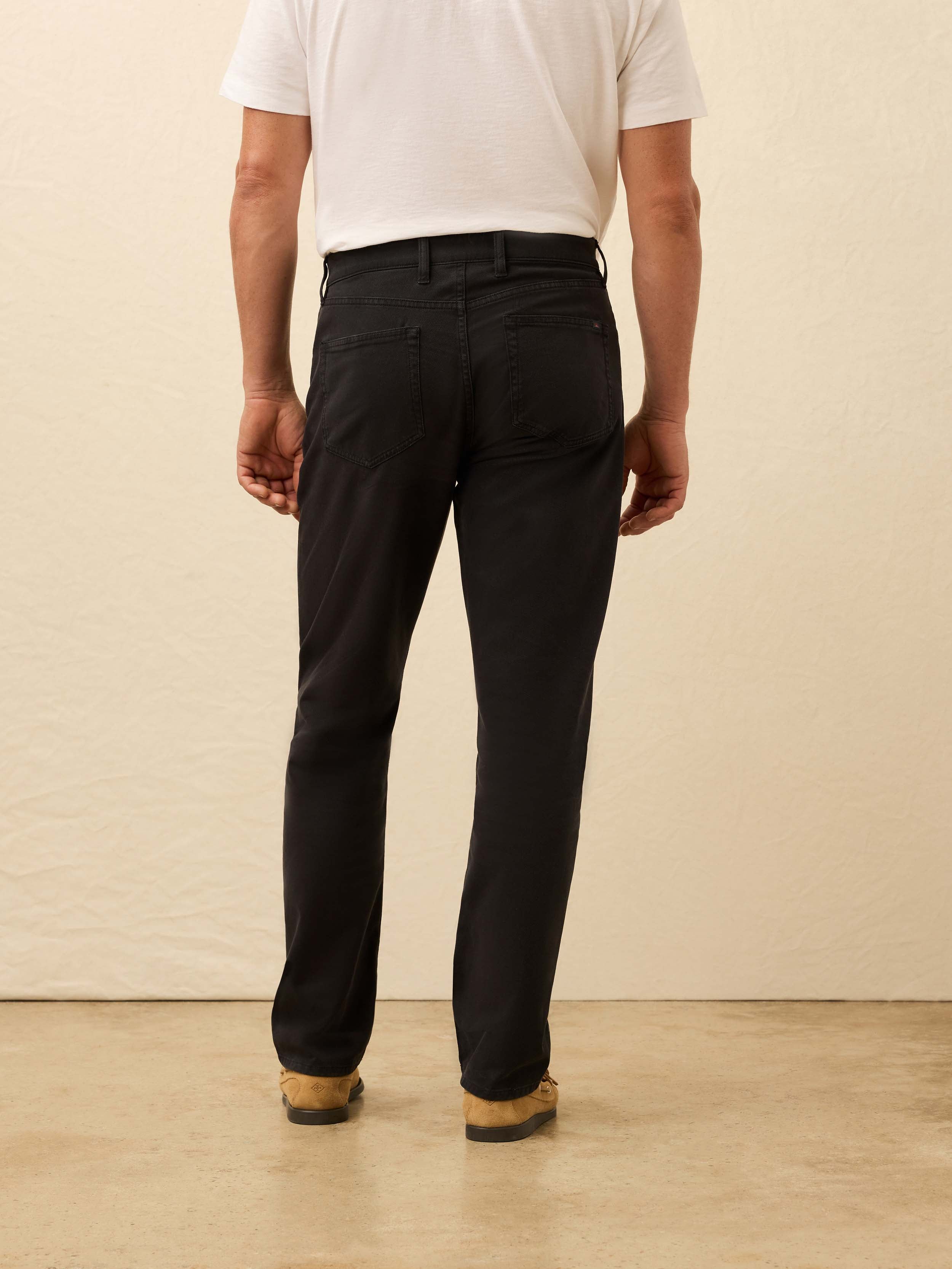 Person wearing black pants with a white tee against a beige background