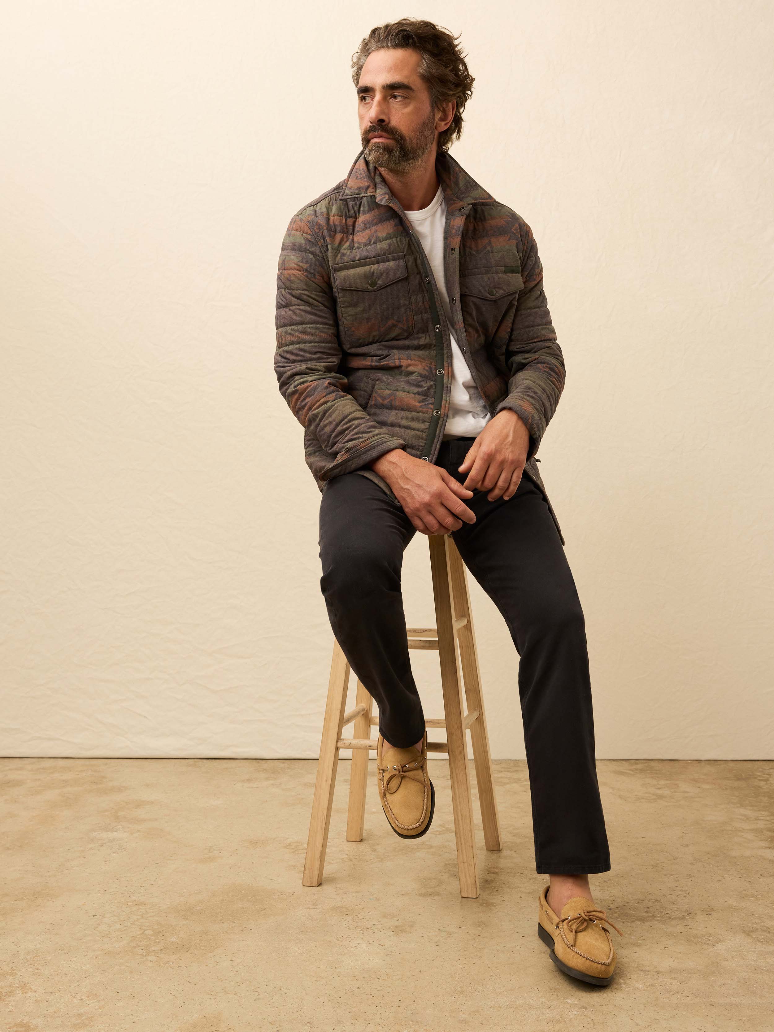 Man wearing black pants with a white tee on a beige background