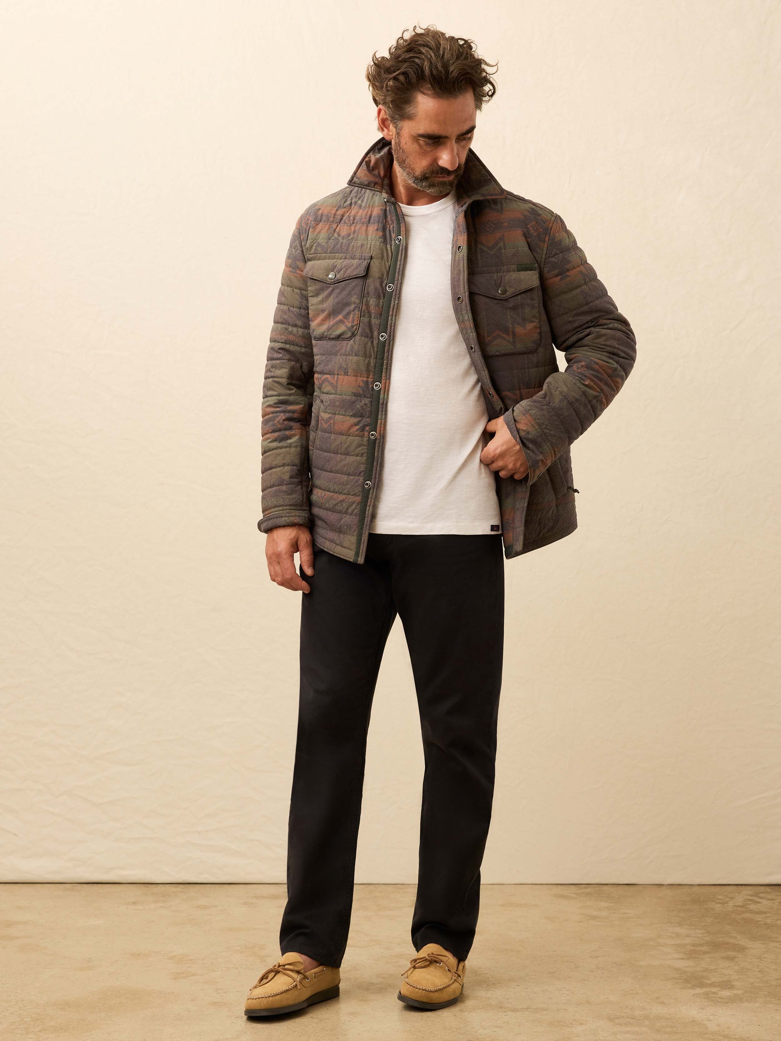 Man wearing black pants with a quilted jacket on a beige background