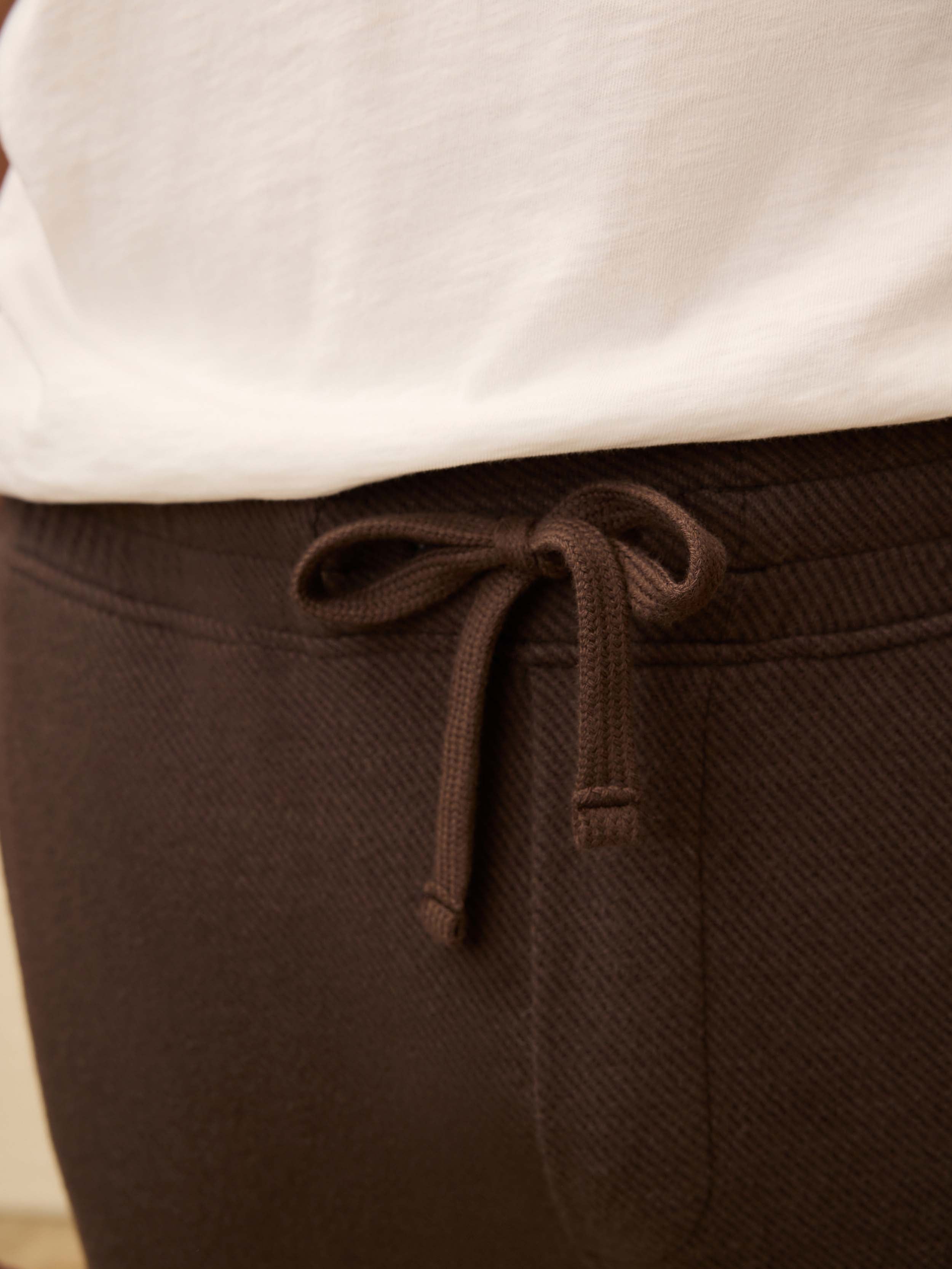 Brown sweatpants with a drawstring on a neutral background