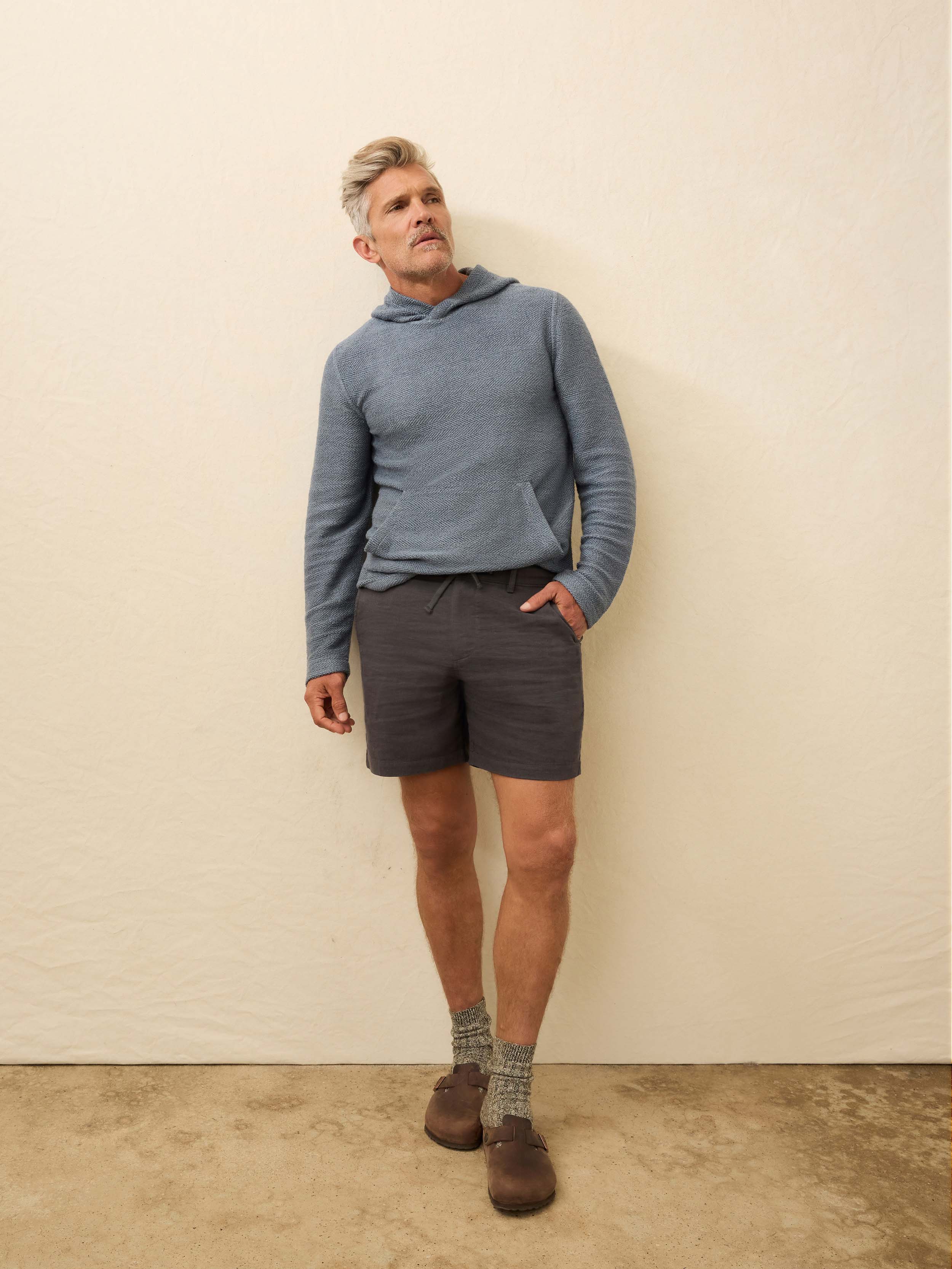 Man wearing black linen shorts against a beige background