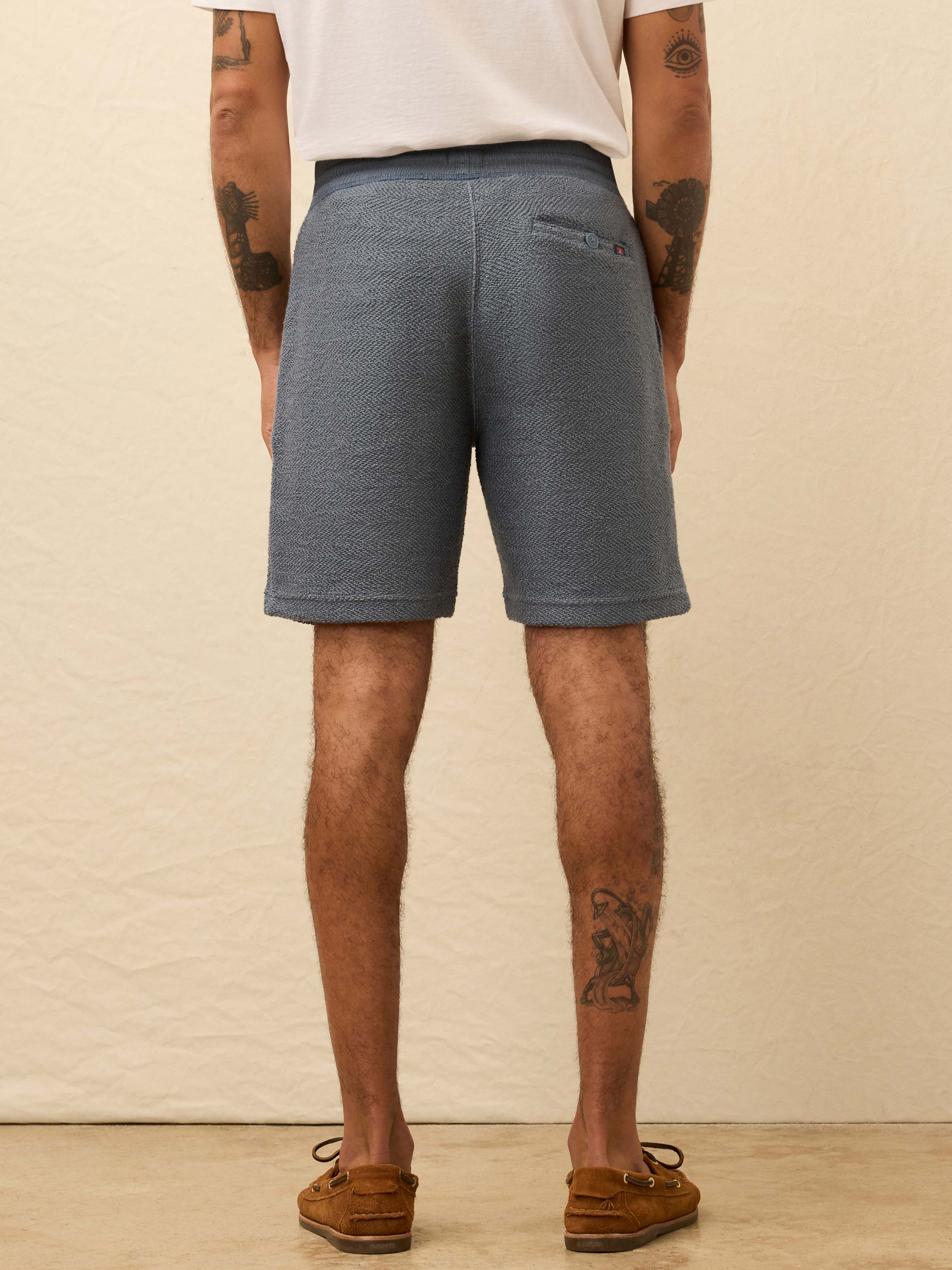 Man wearing blue shorts against a beige background