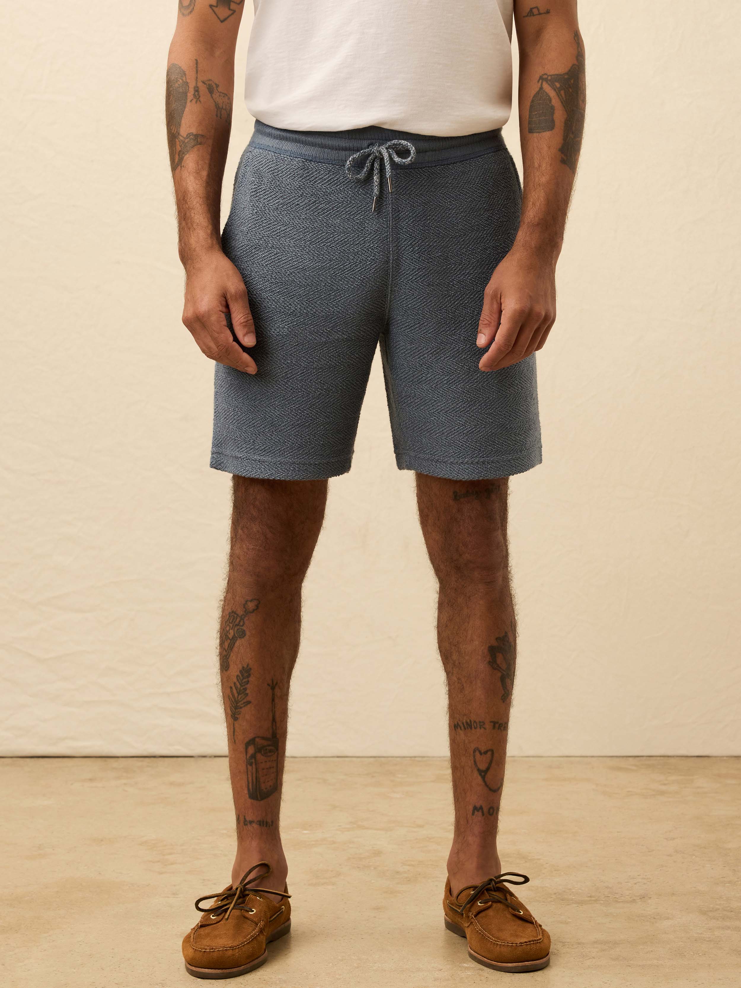 Man wearing blue shorts against a beige background