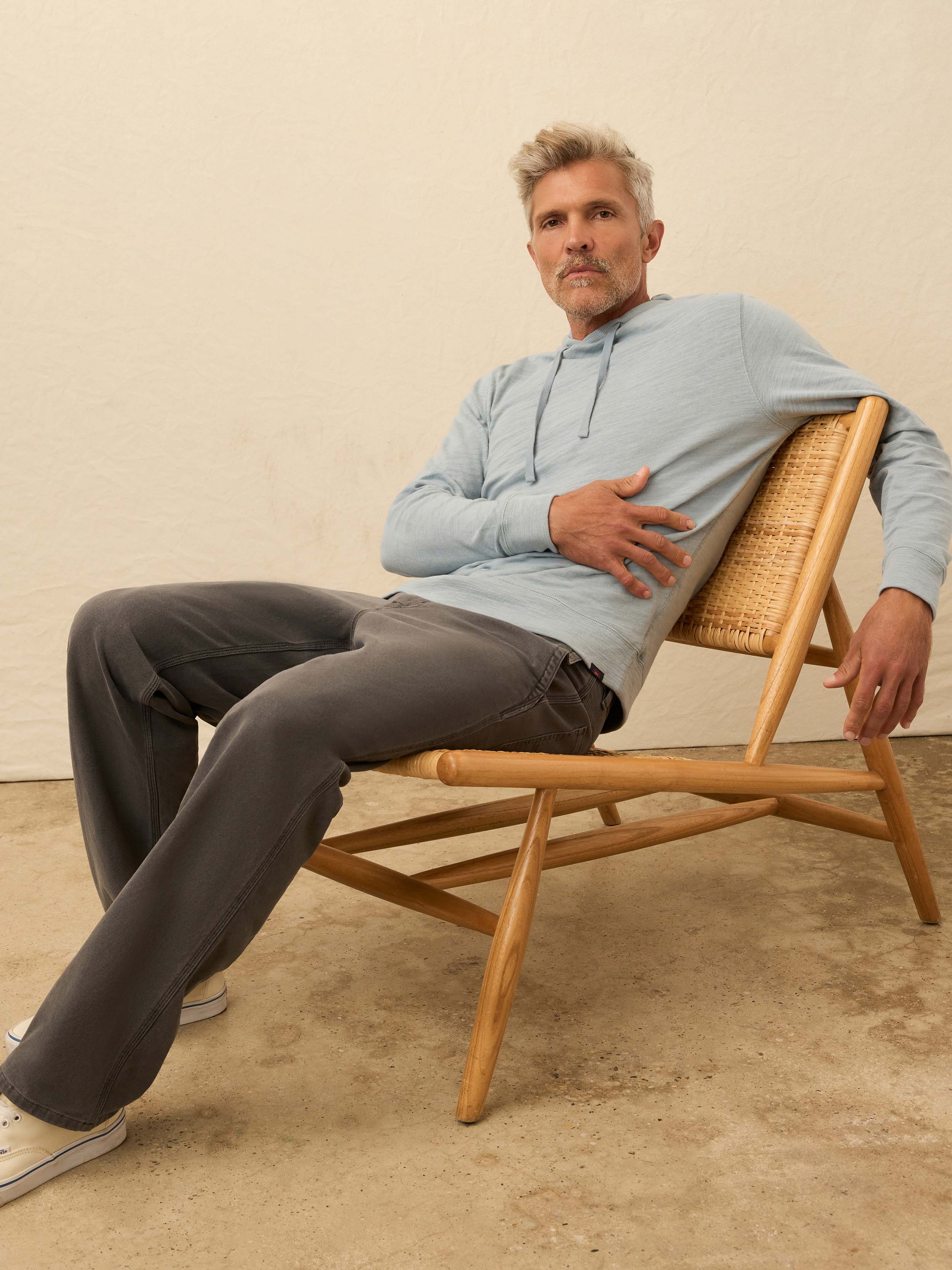 Man wearing a light blue hoodie against a beige wall