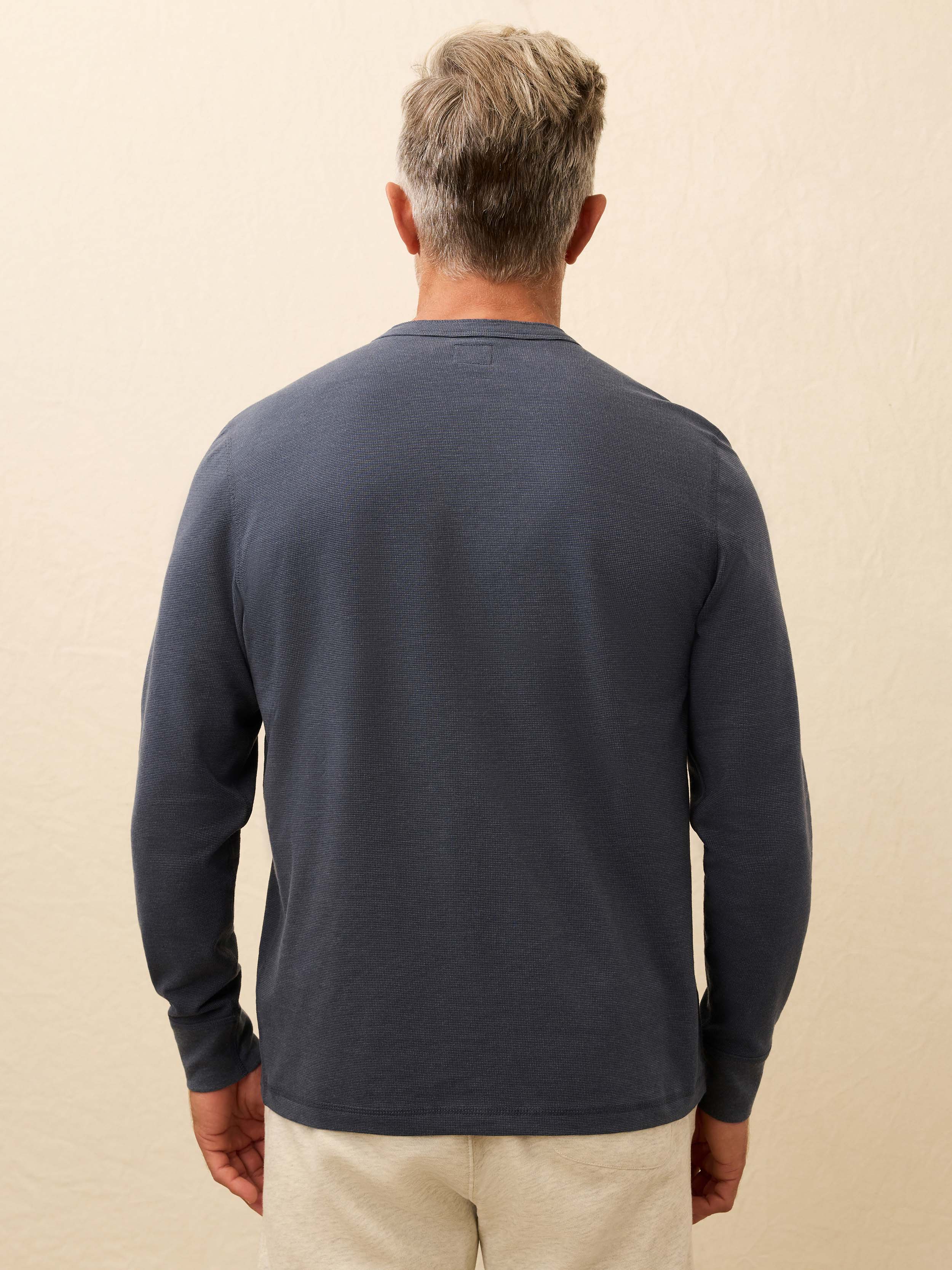 Man wearing a navy blue long-sleeve shirt against a beige background