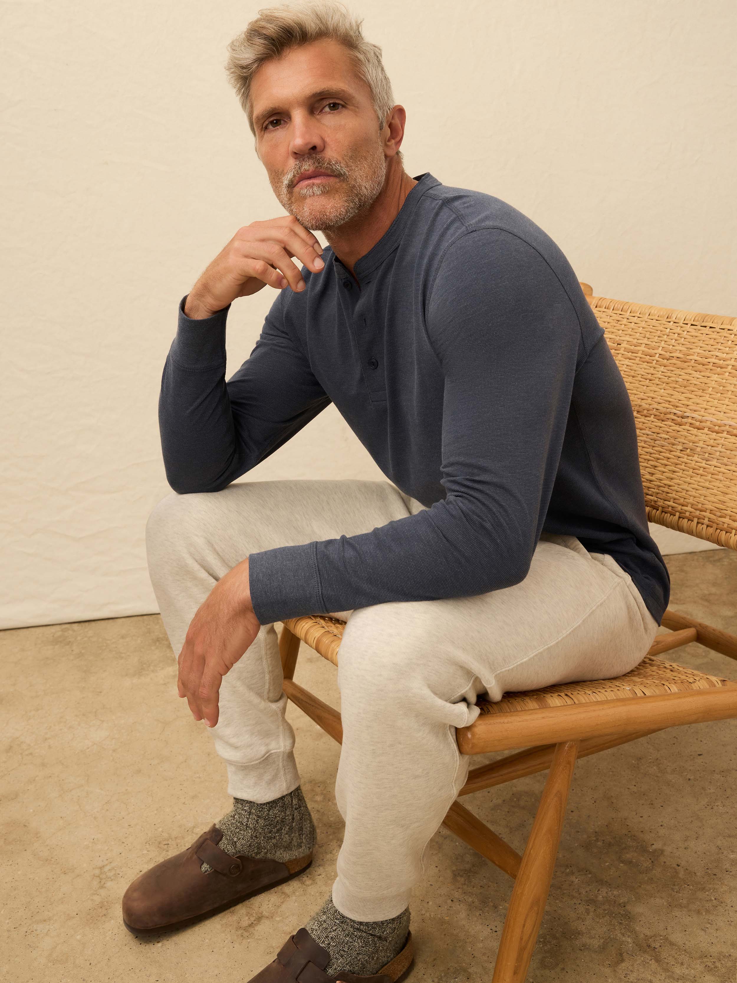 Man wearing a navy blue long-sleeve shirt against a beige background