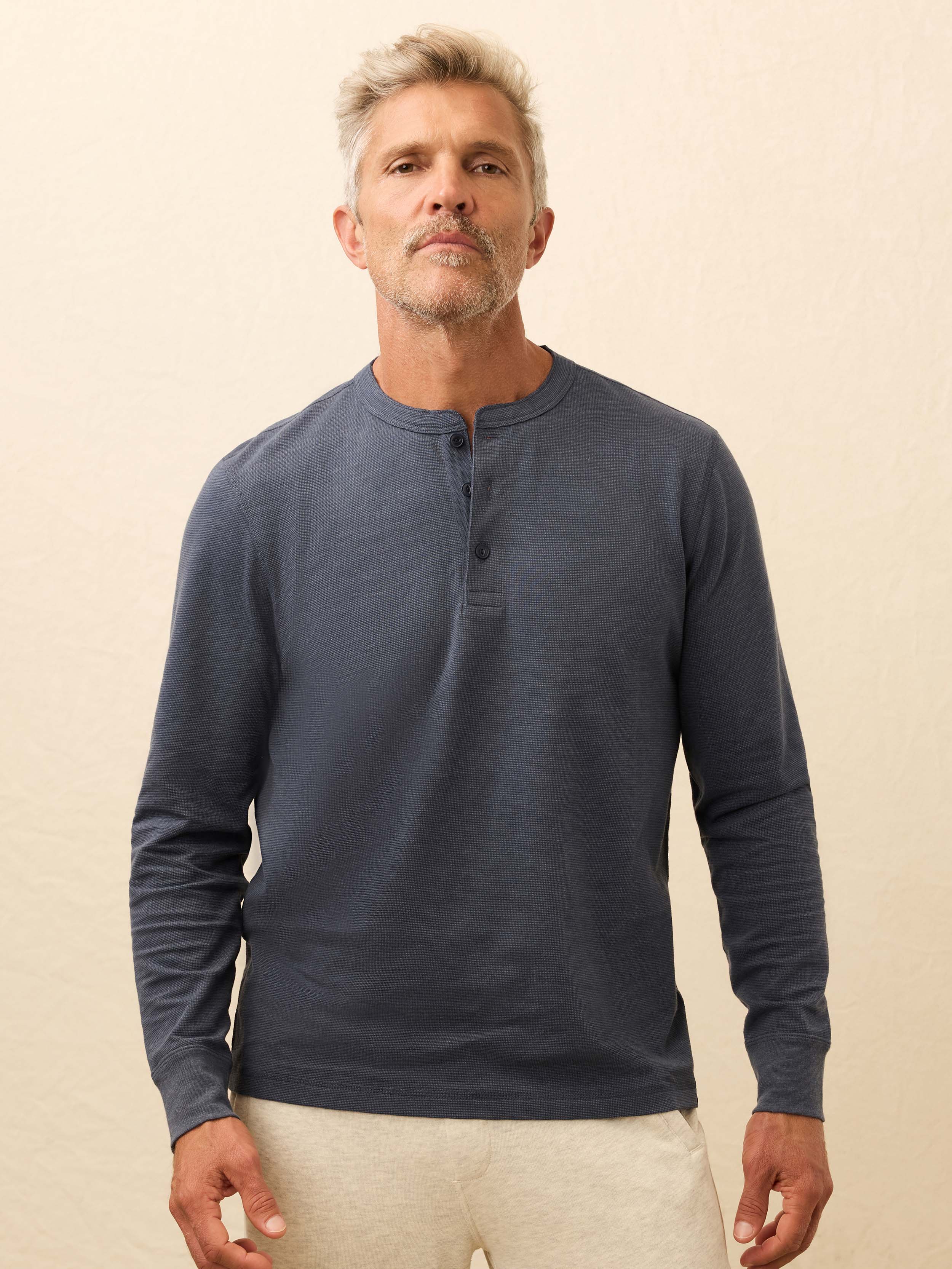Man wearing a navy blue long-sleeve shirt against a beige background