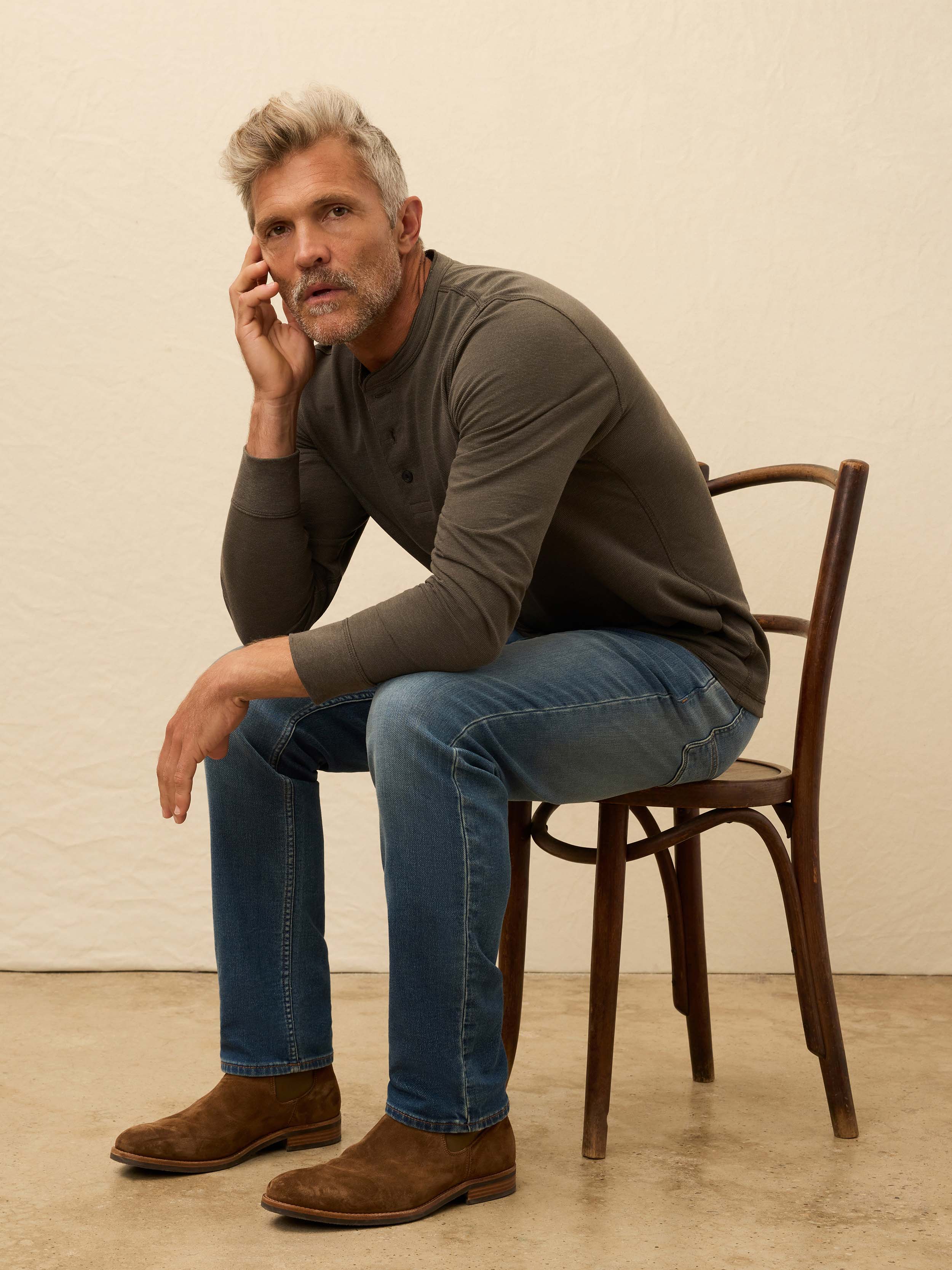 Man wearing a brown long sleeve henley shirt against a beige background