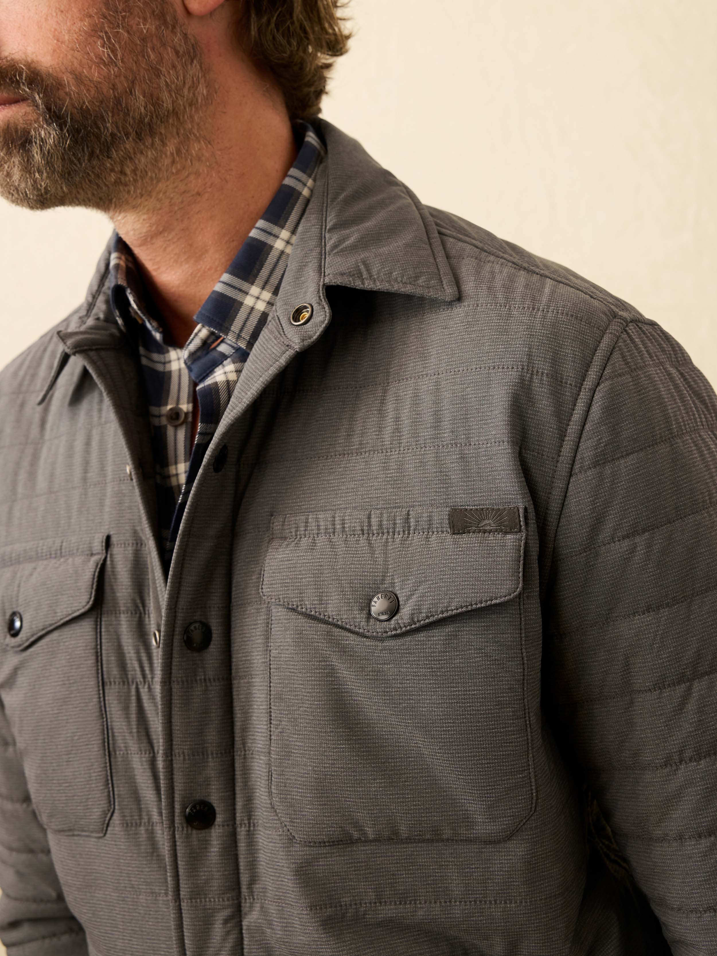 Man wearing a gray quilted jacket against a beige background