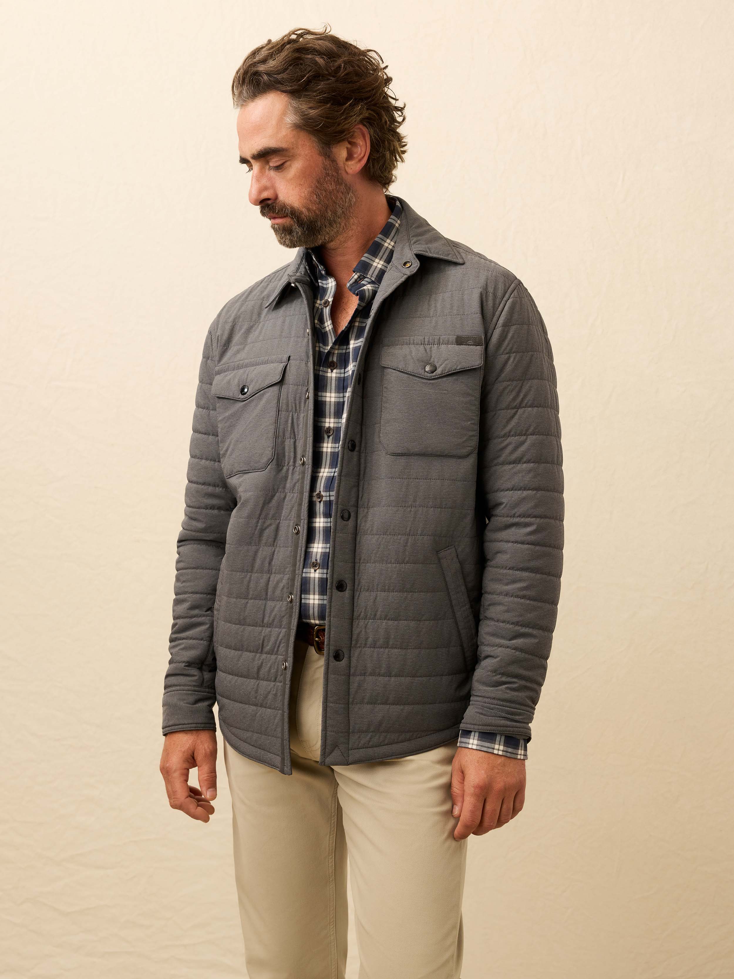 Man wearing a gray quilted jacket against a beige background