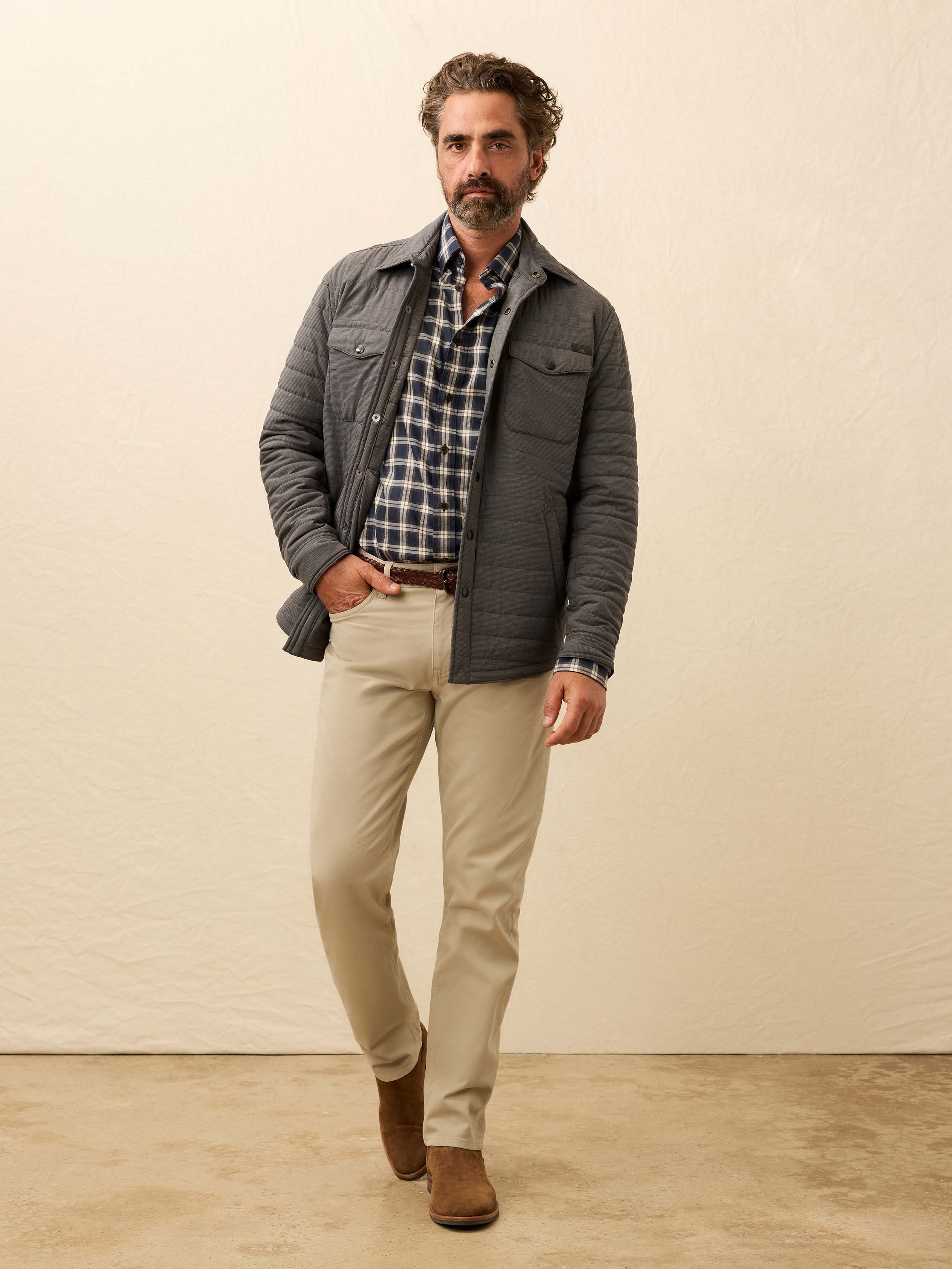 Man wearing a gray quilted jacket against a beige background