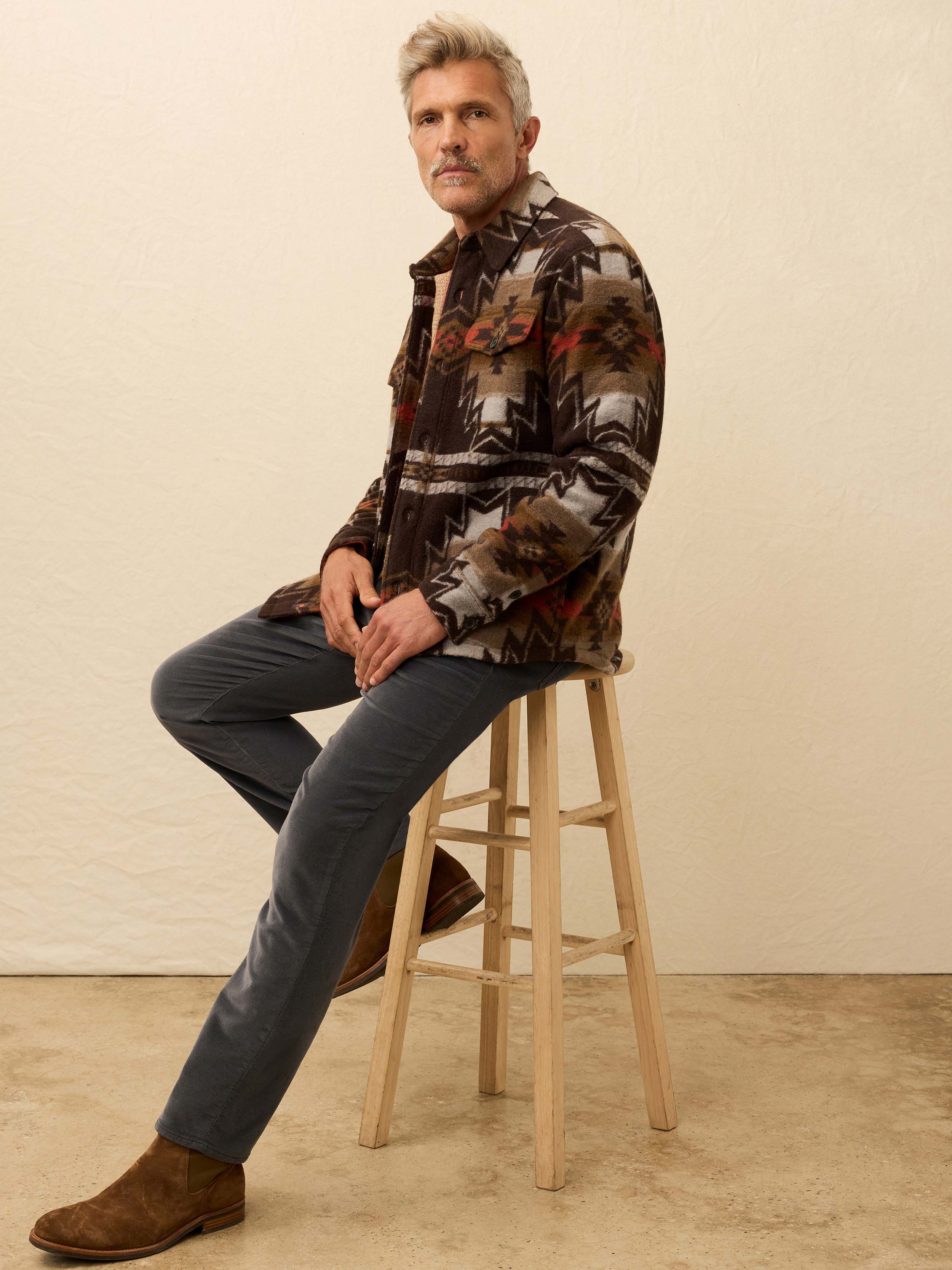 Man wearing a Native American patterned jacket with a beige background