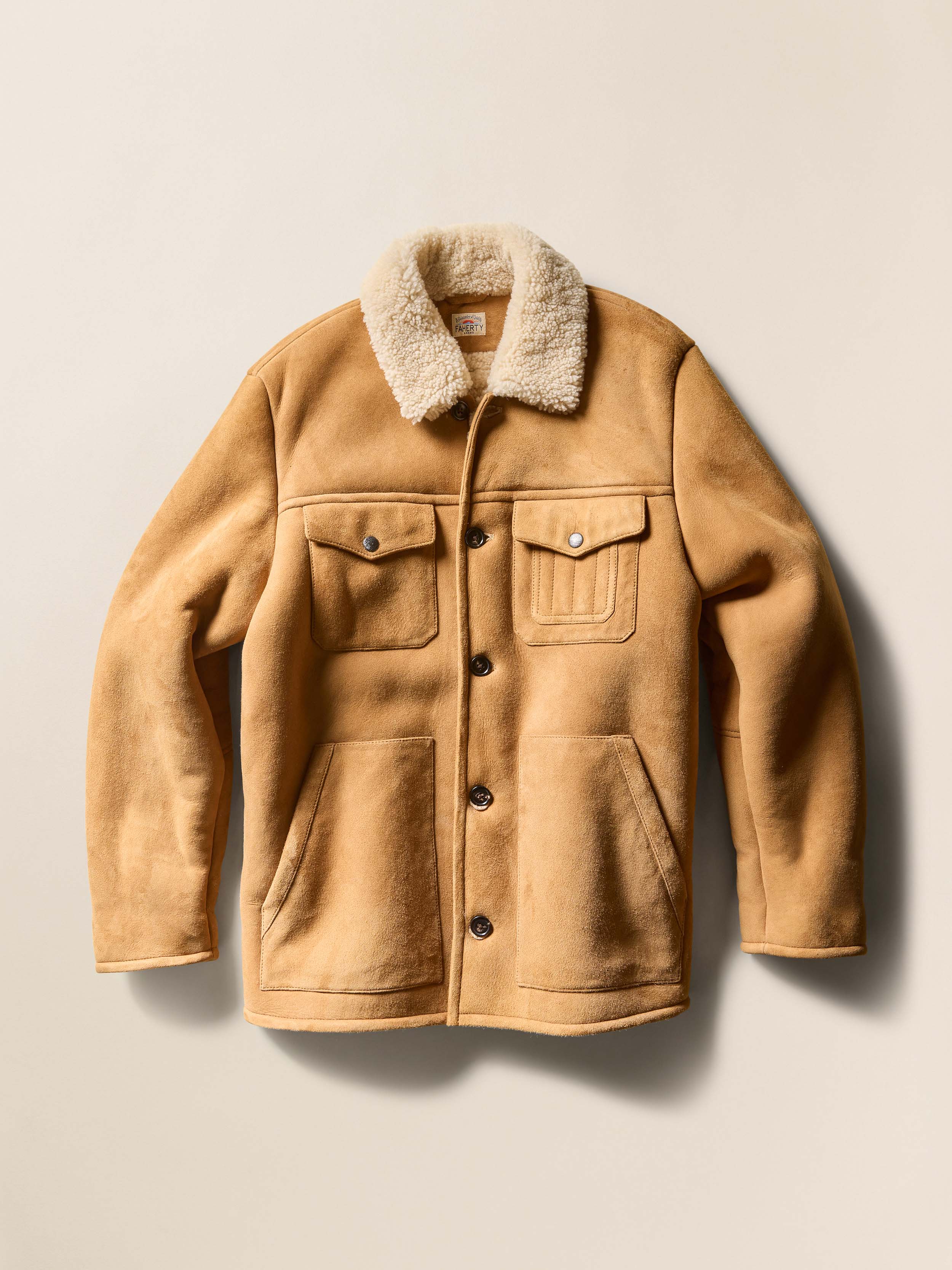 Brown suede jacket with shearling collar on a beige background