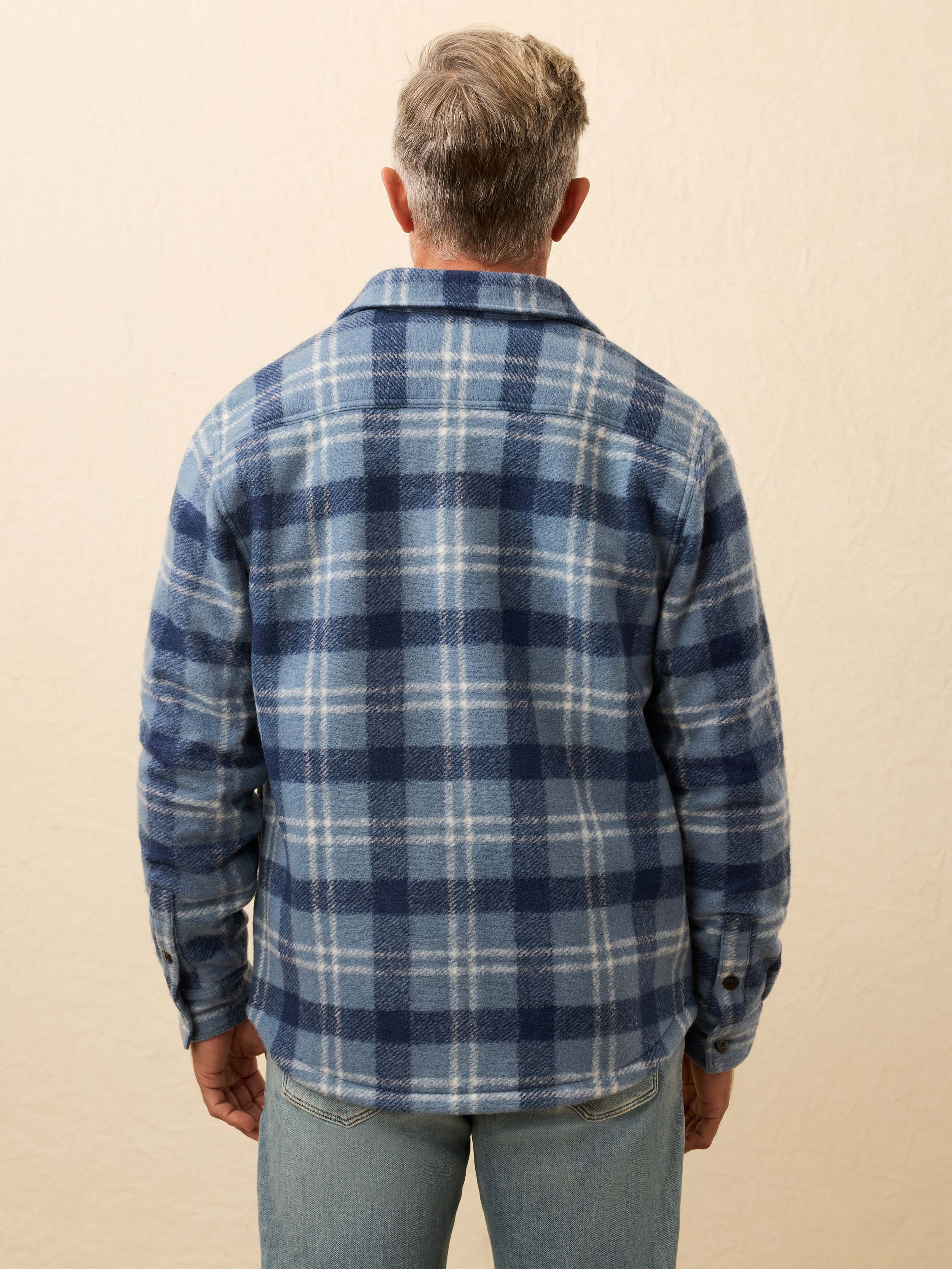 Man wearing a blue flannel shirt jacket against a beige background