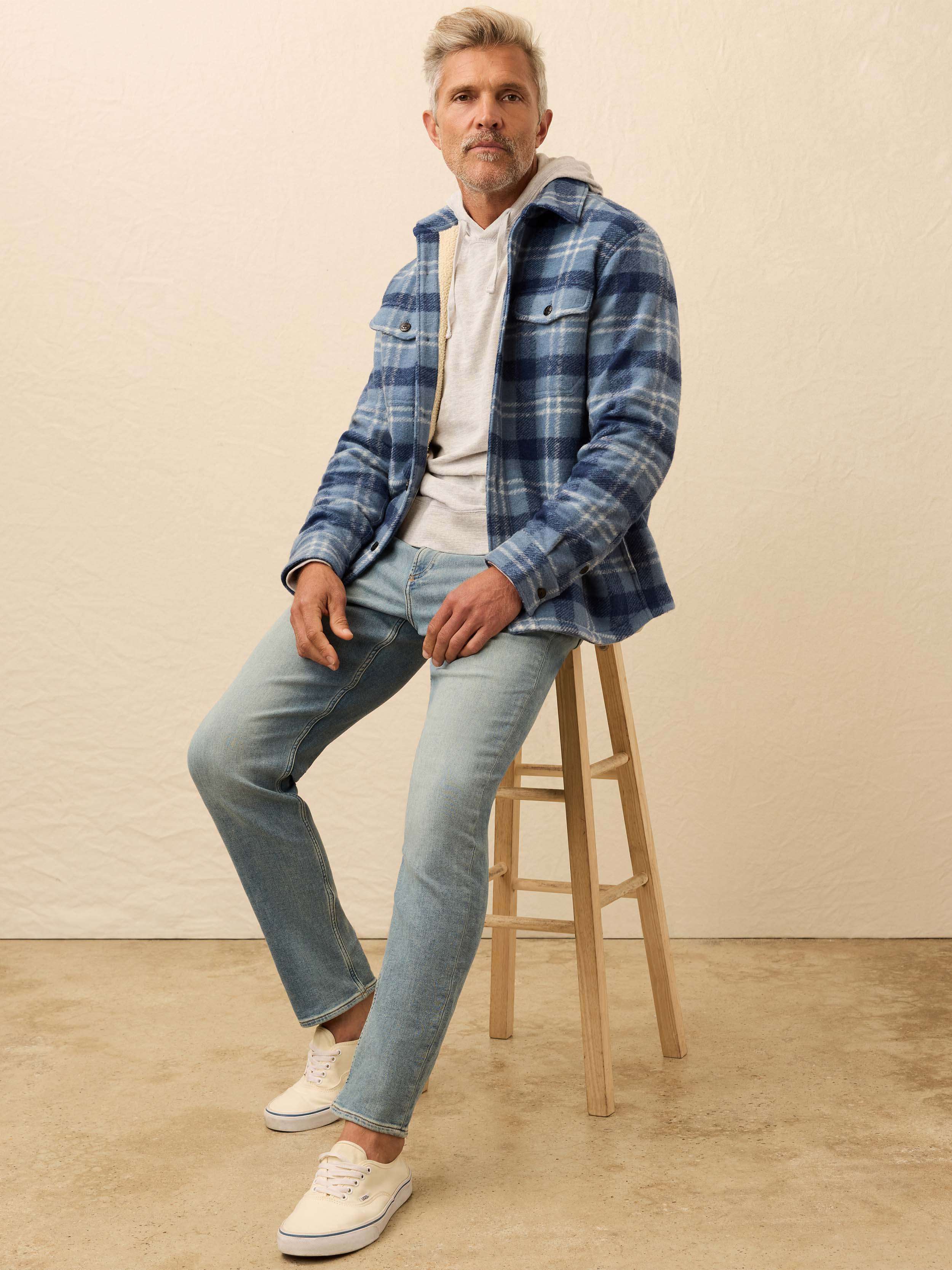 Man wearing a blue flannel shirt jacket against a beige background