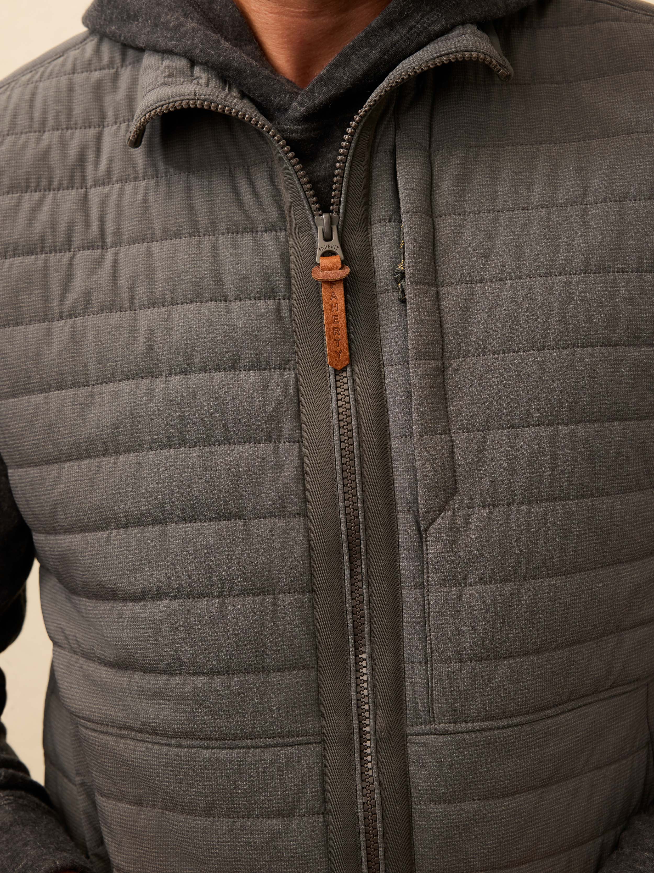 Close up of a man wearing a grey quilted vest 