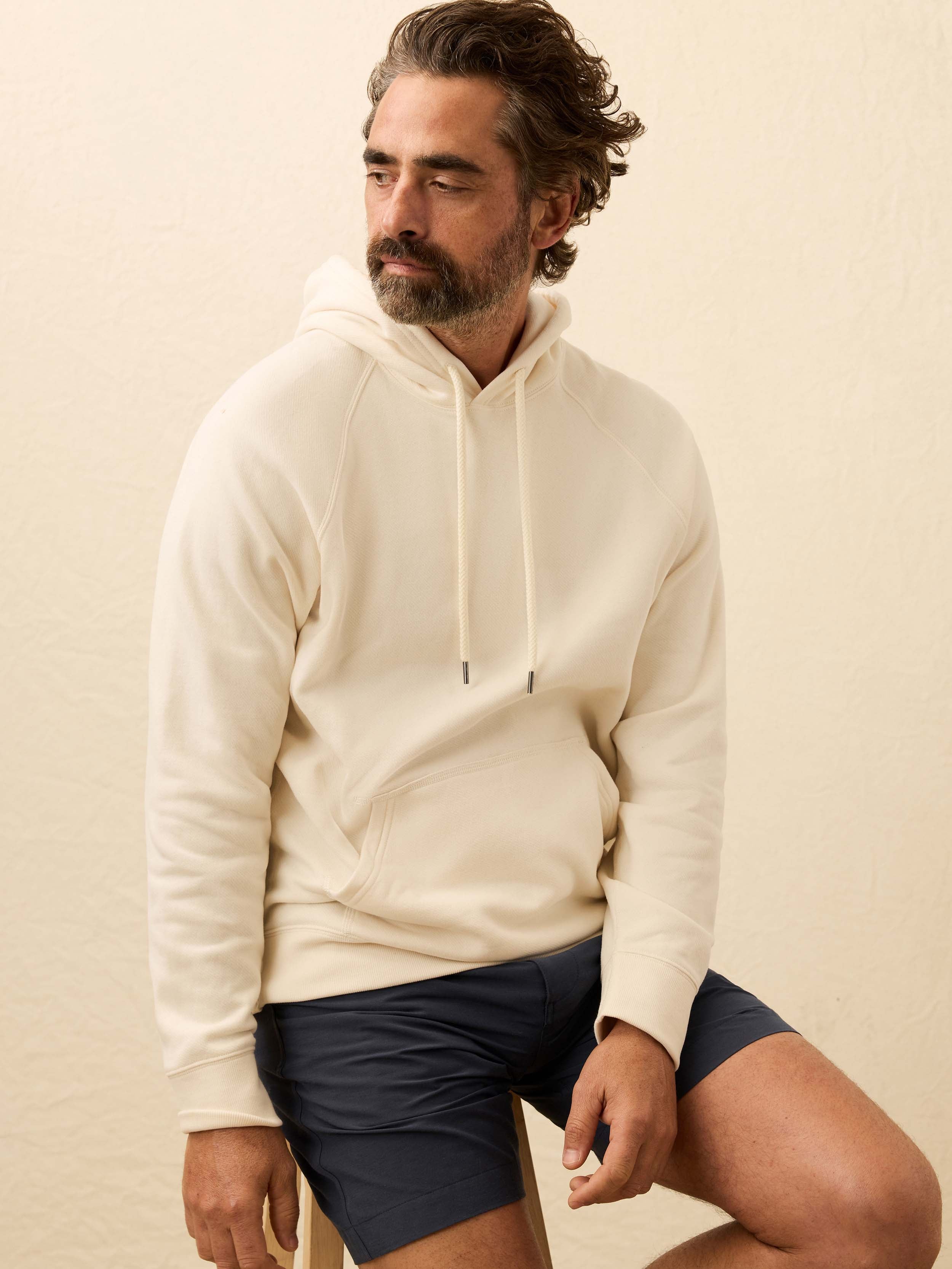 Man wearing a cream hoodie against a beige background