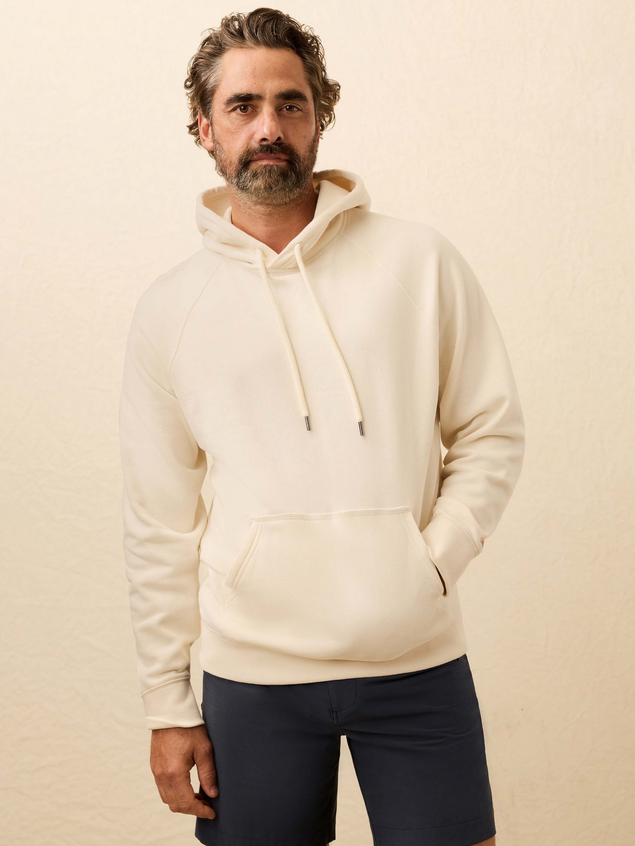 Man wearing a cream hoodie against a beige background