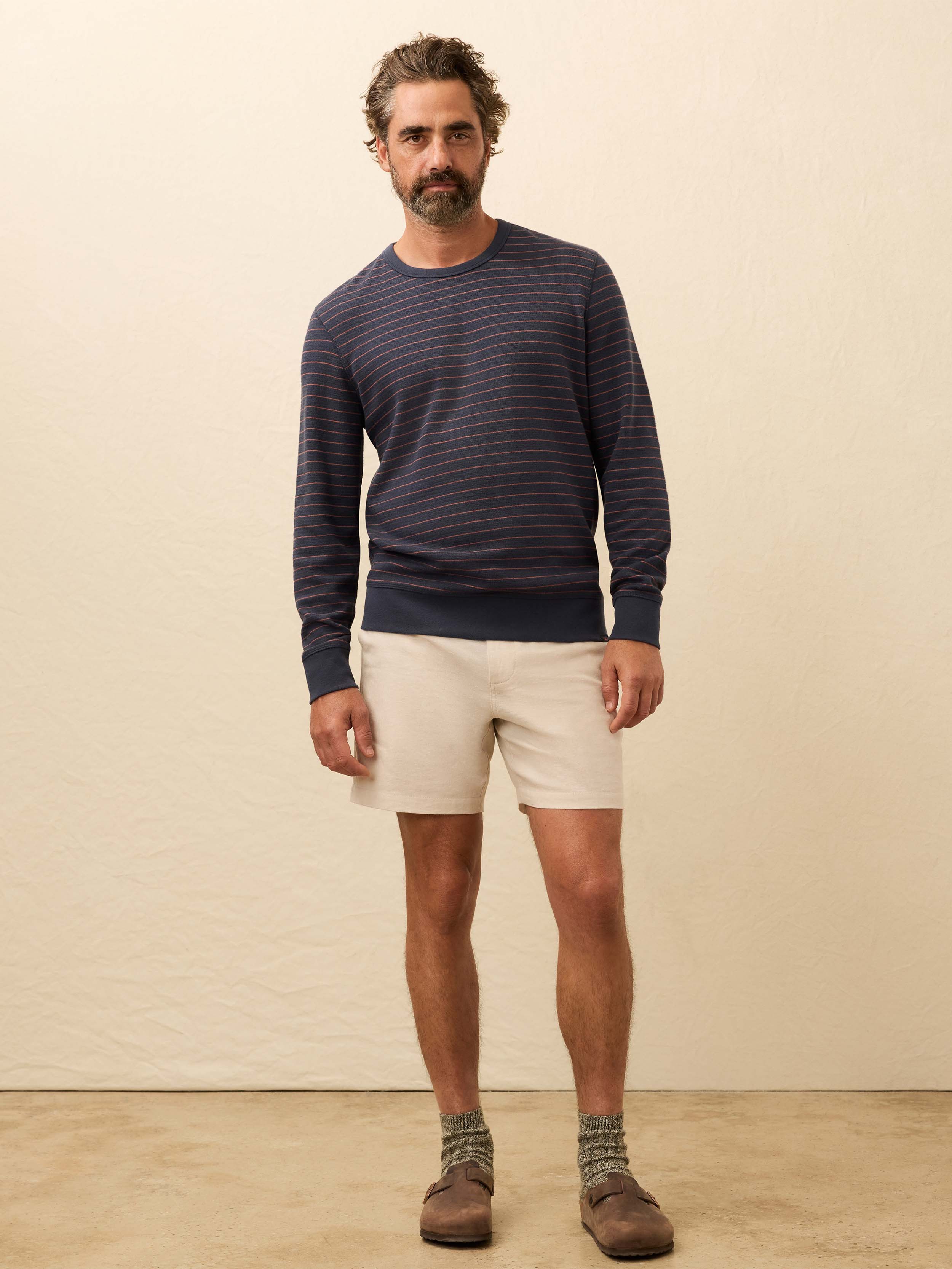 Man wearing a navy and red striped long sleeve shirt against a beige background