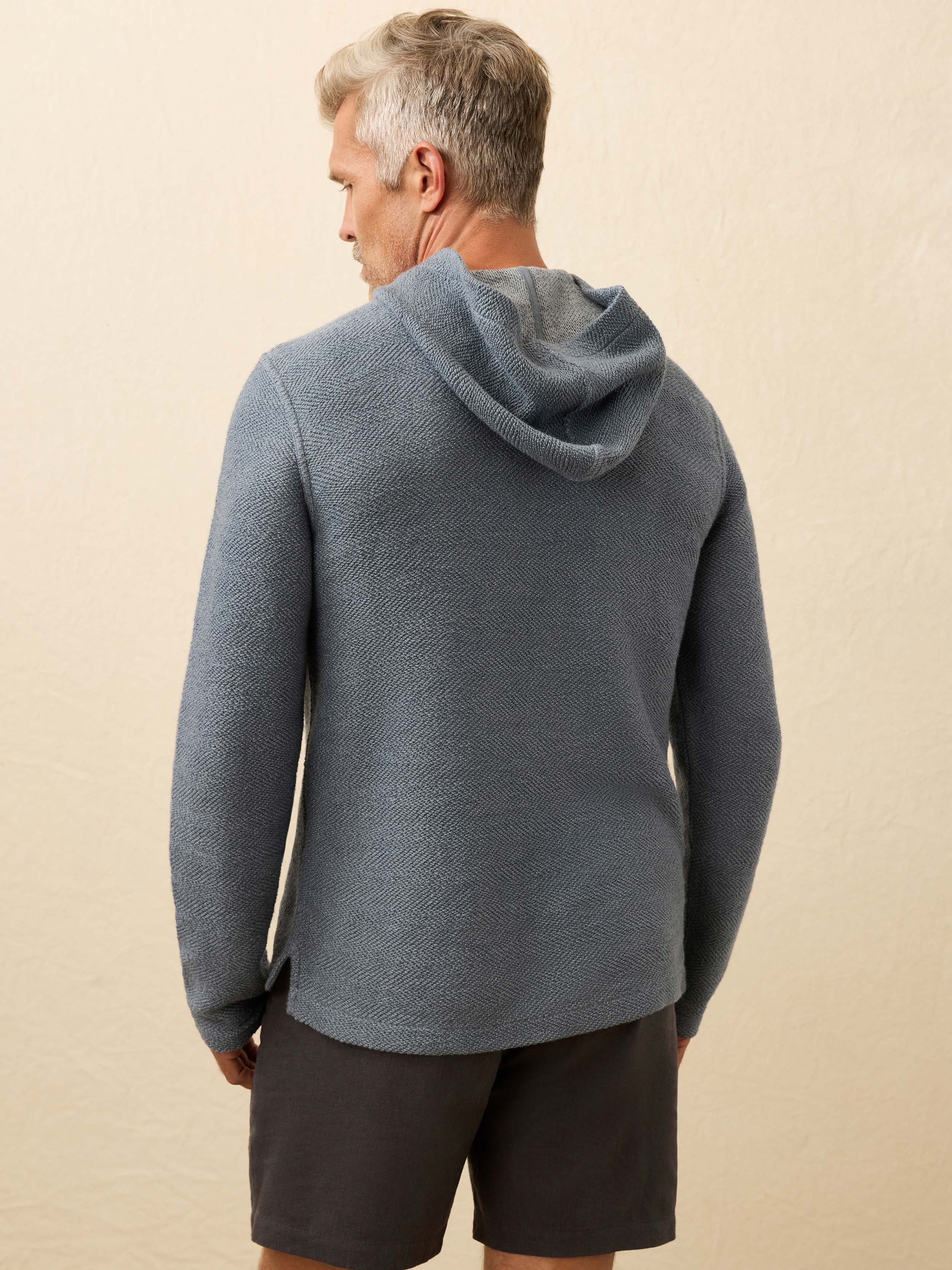 Man wearing a blue hoodie against a beige background