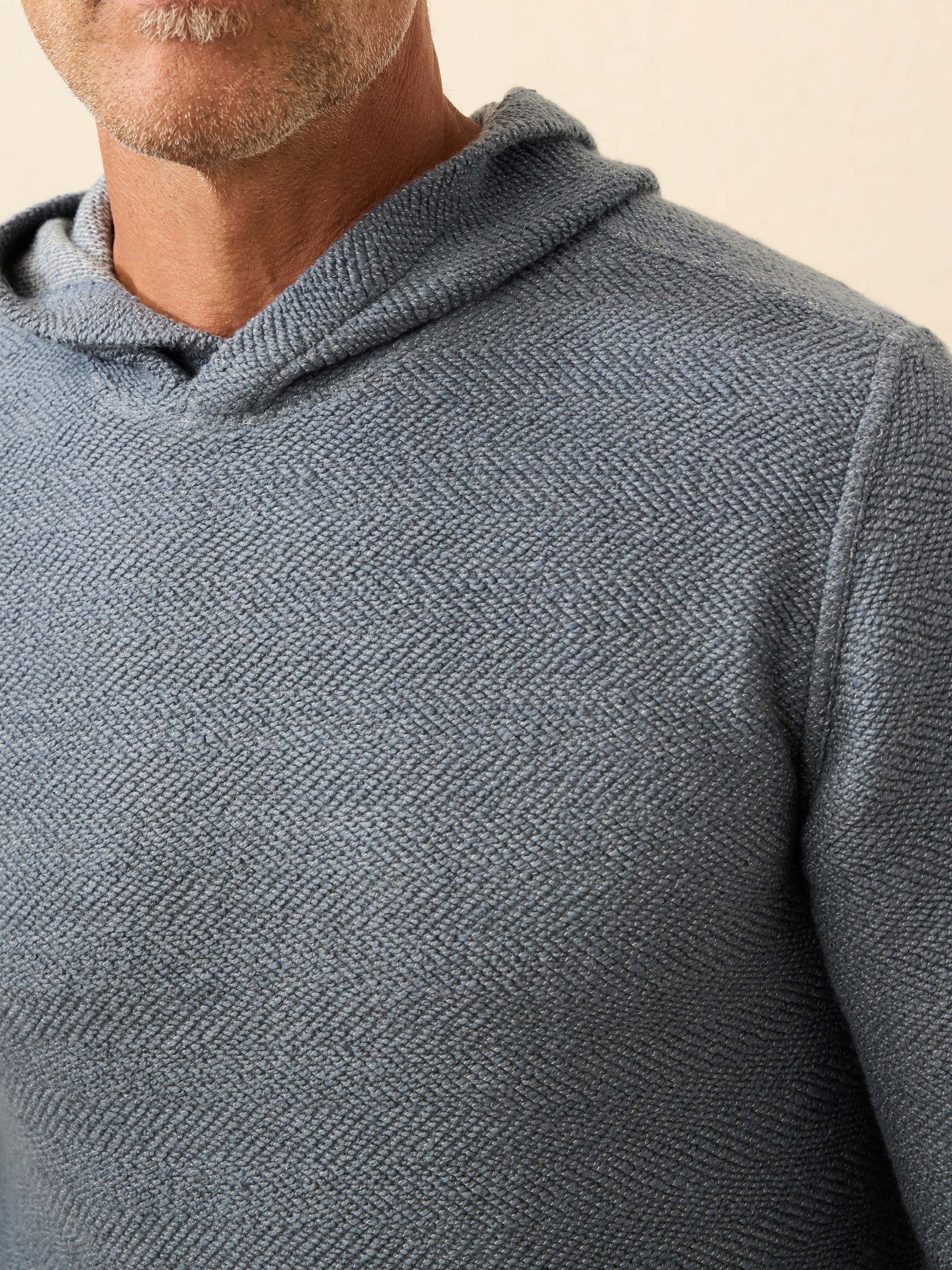 Man wearing a blue hoodie against a beige background