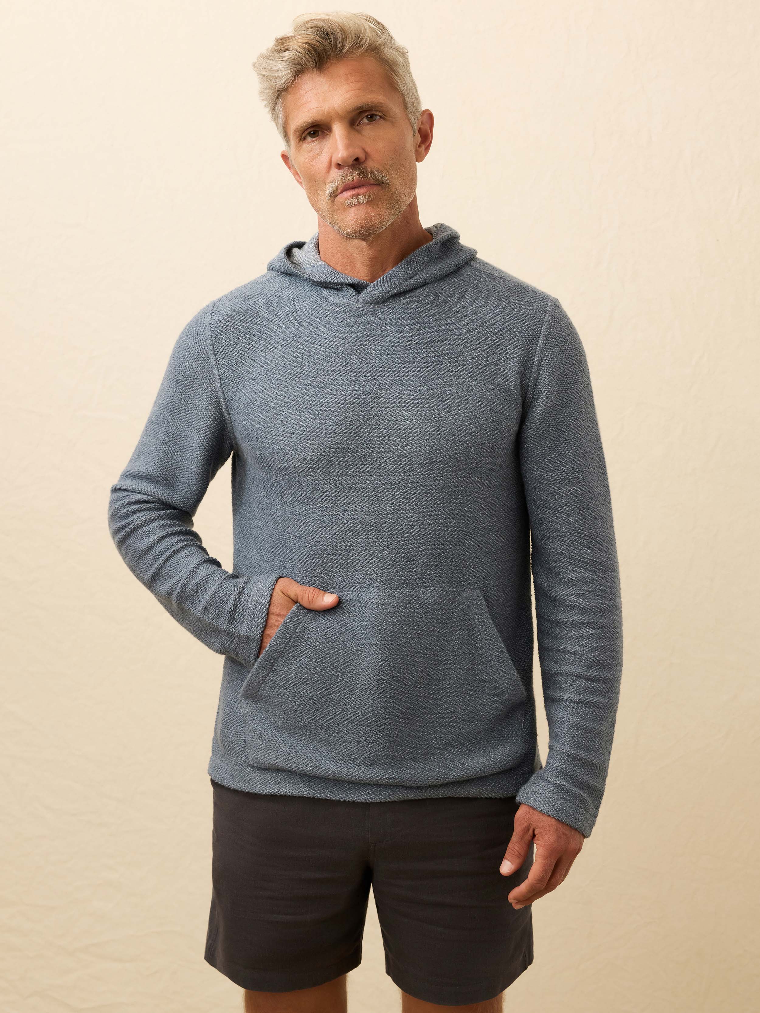 Man wearing a blue hoodie against a beige background