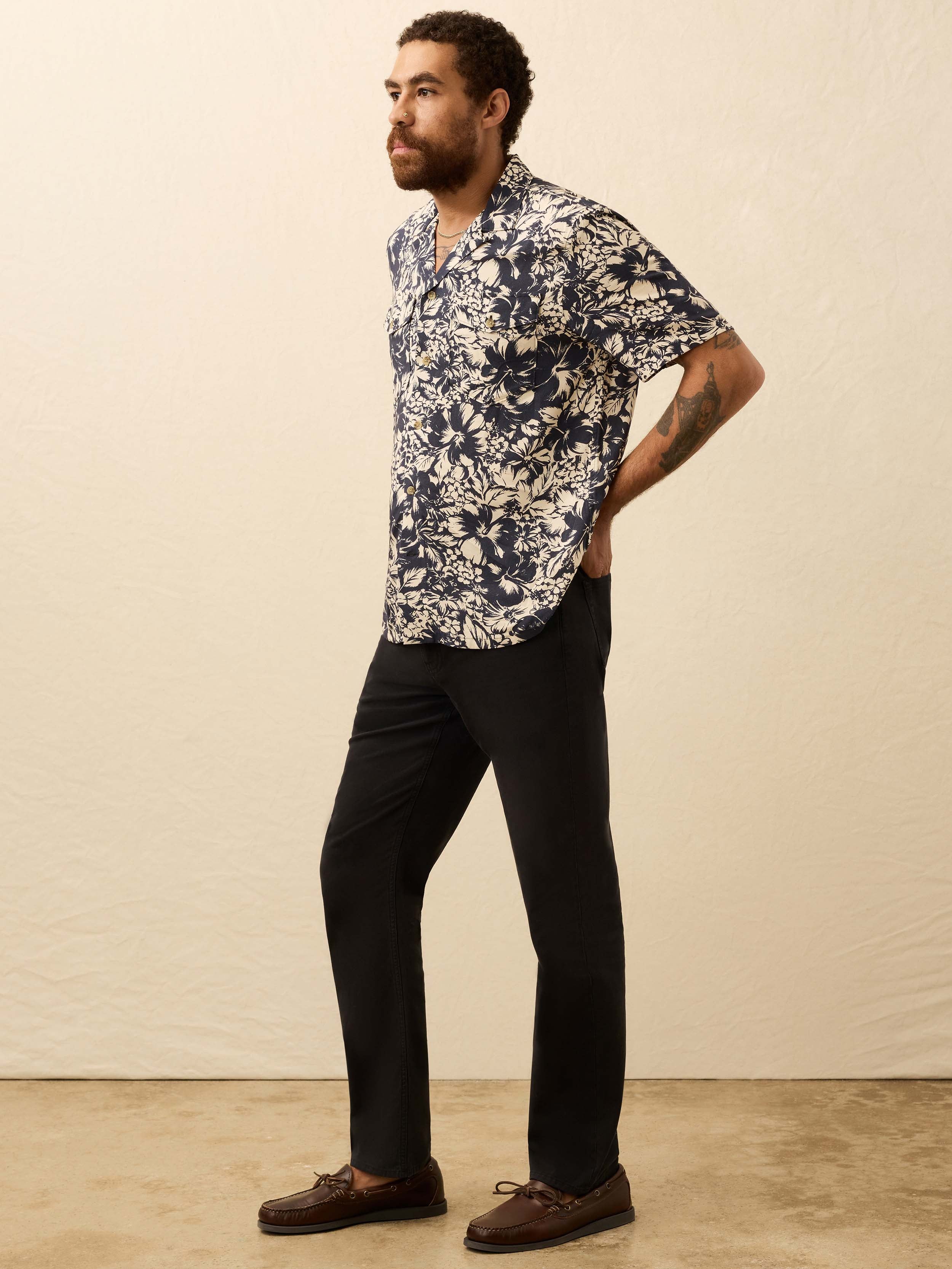 Man wearing a navy and cream floral shirt against a beige background