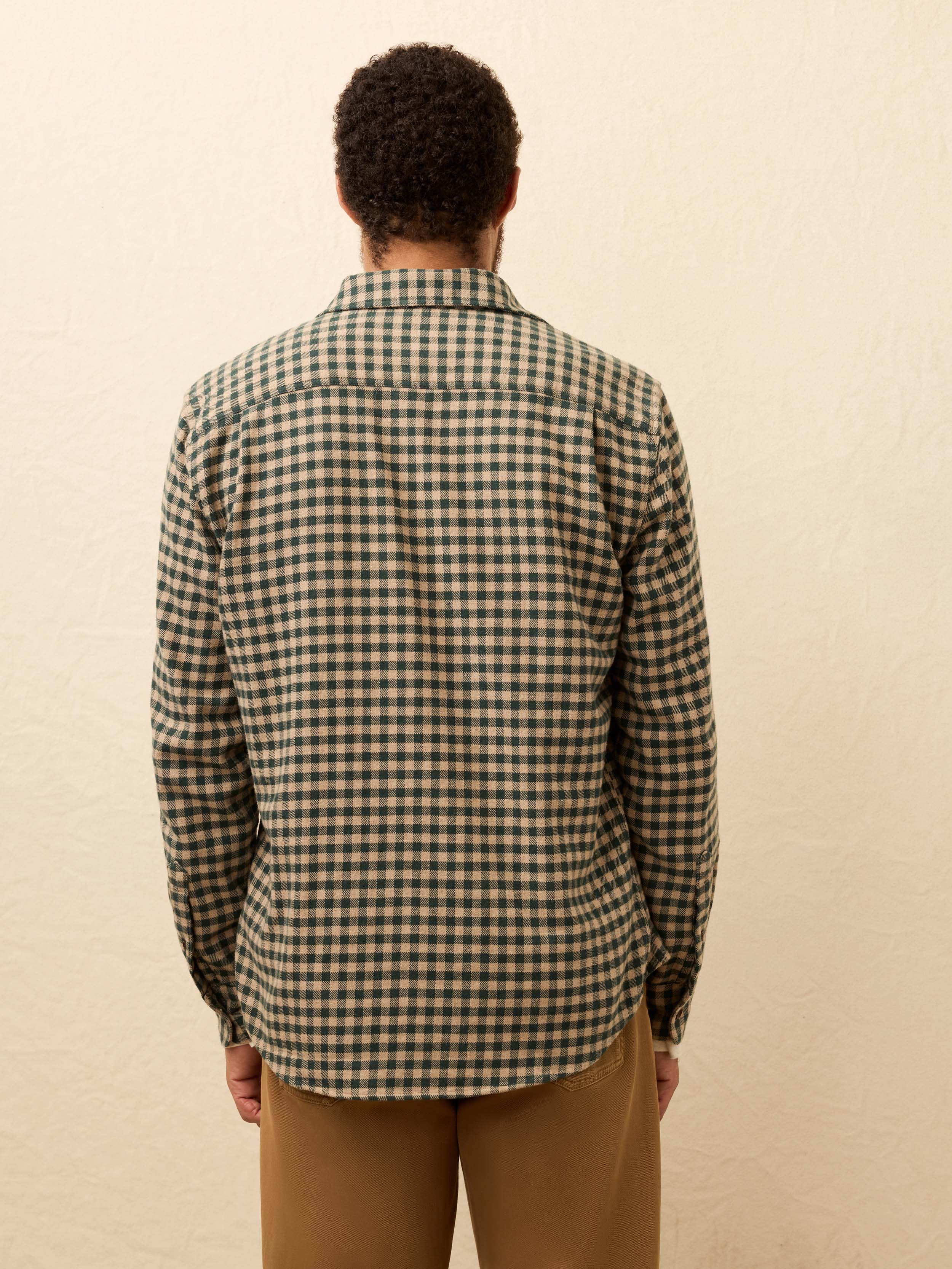 Man wearing a beige and green gingham shirt against a beige background