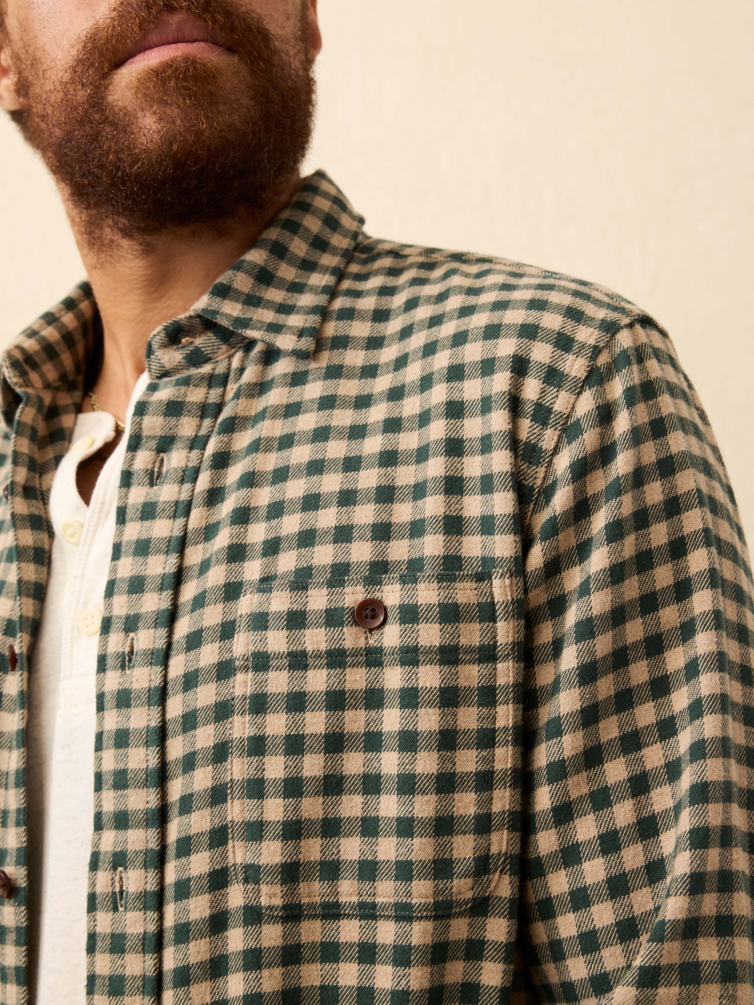 Man wearing a beige and green gingham shirt against a beige background