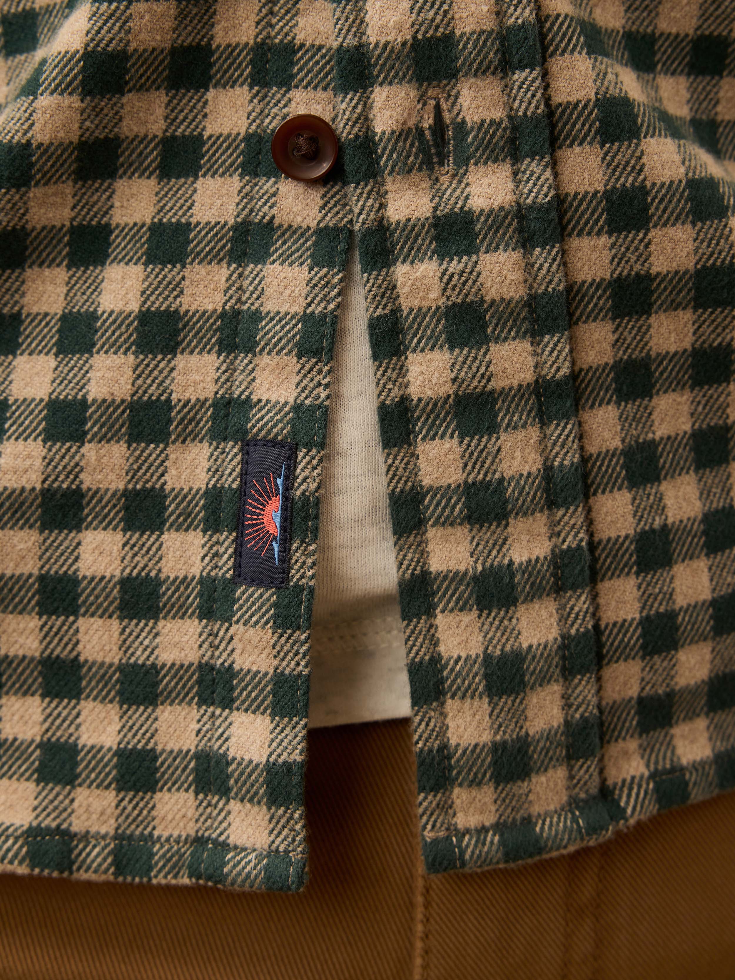 Man wearing a beige and green gingham shirt with a Faherty brand logo