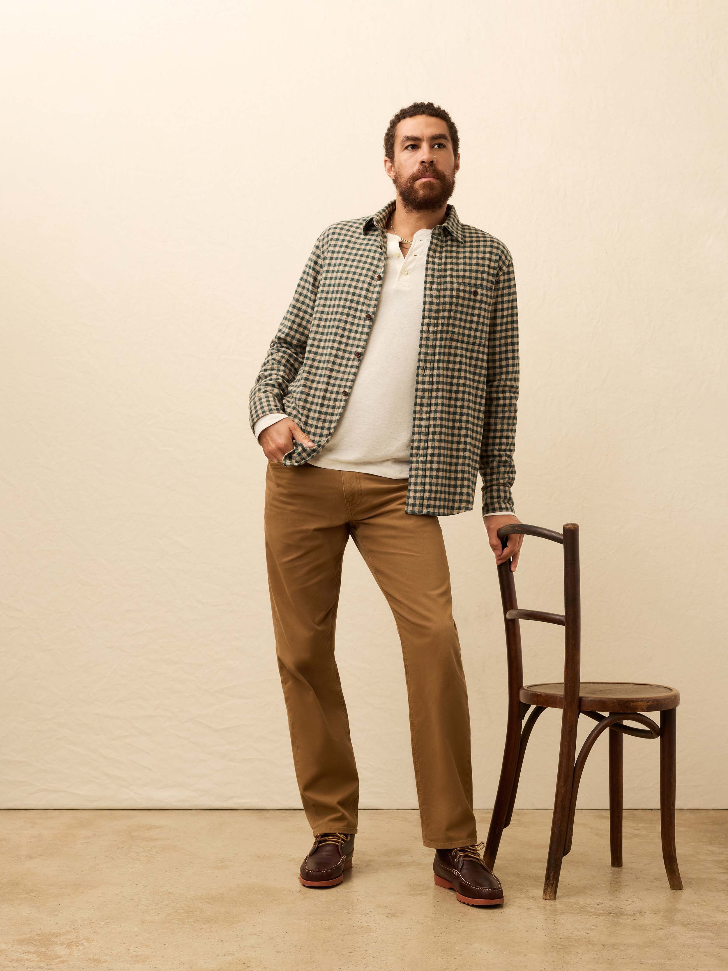 Man wearing a beige and green gingham shirt against a beige background