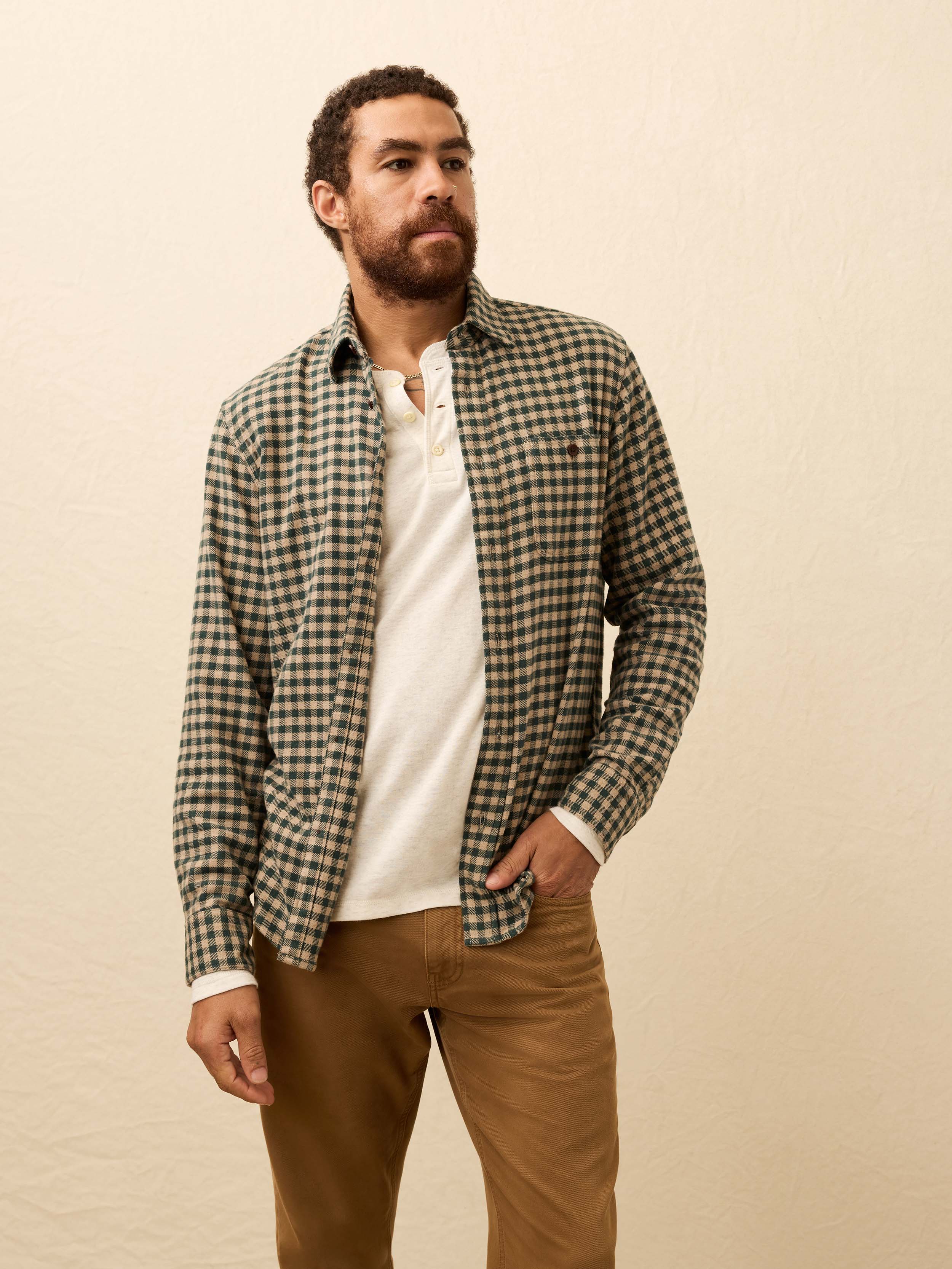 Man wearing a beige and green gingham shirt against a beige background