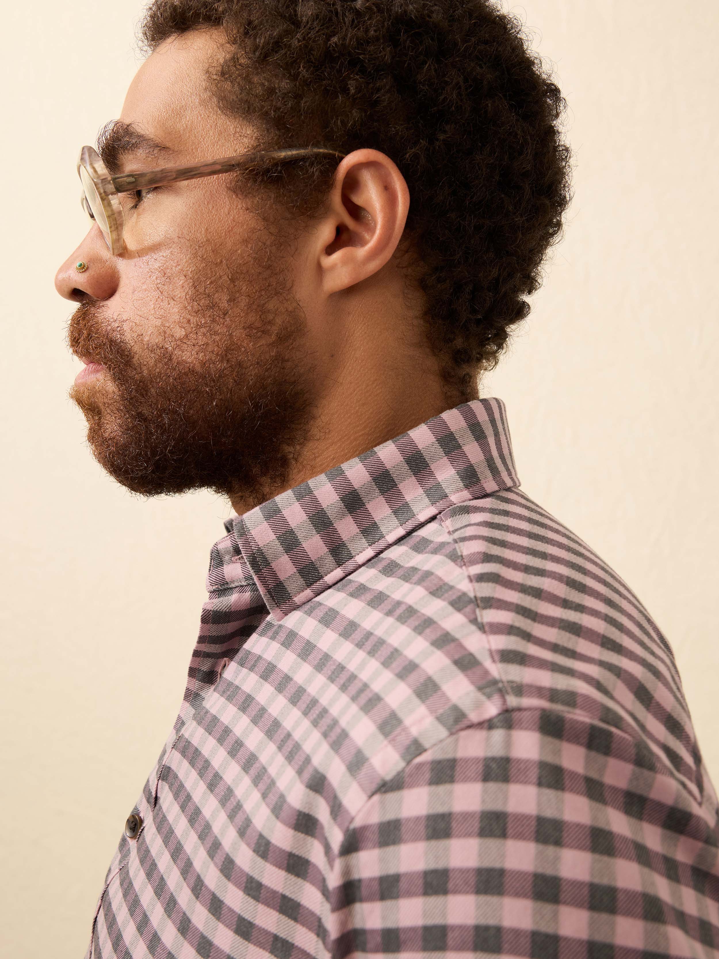 Man wearing a pink and grey gingham shirt against a beige background