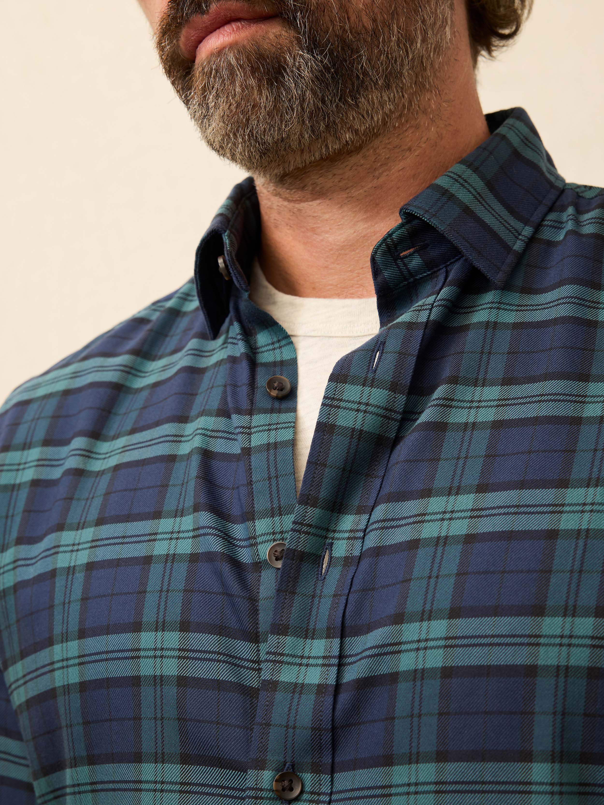 Man wearing a blue and green plaid shirt against a beige background